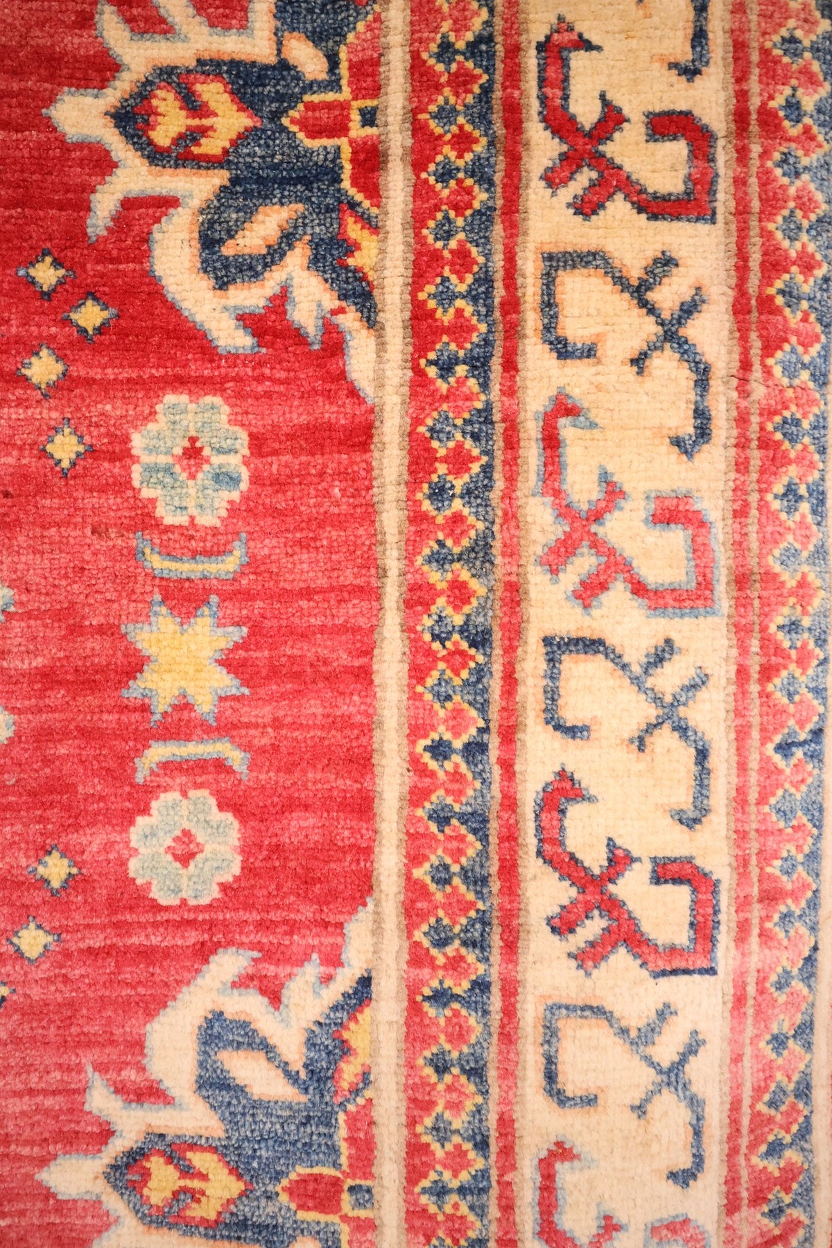 Bordure ivoire à crochets rouges et bleus du Kazak, rosettes et étoiles du champ
