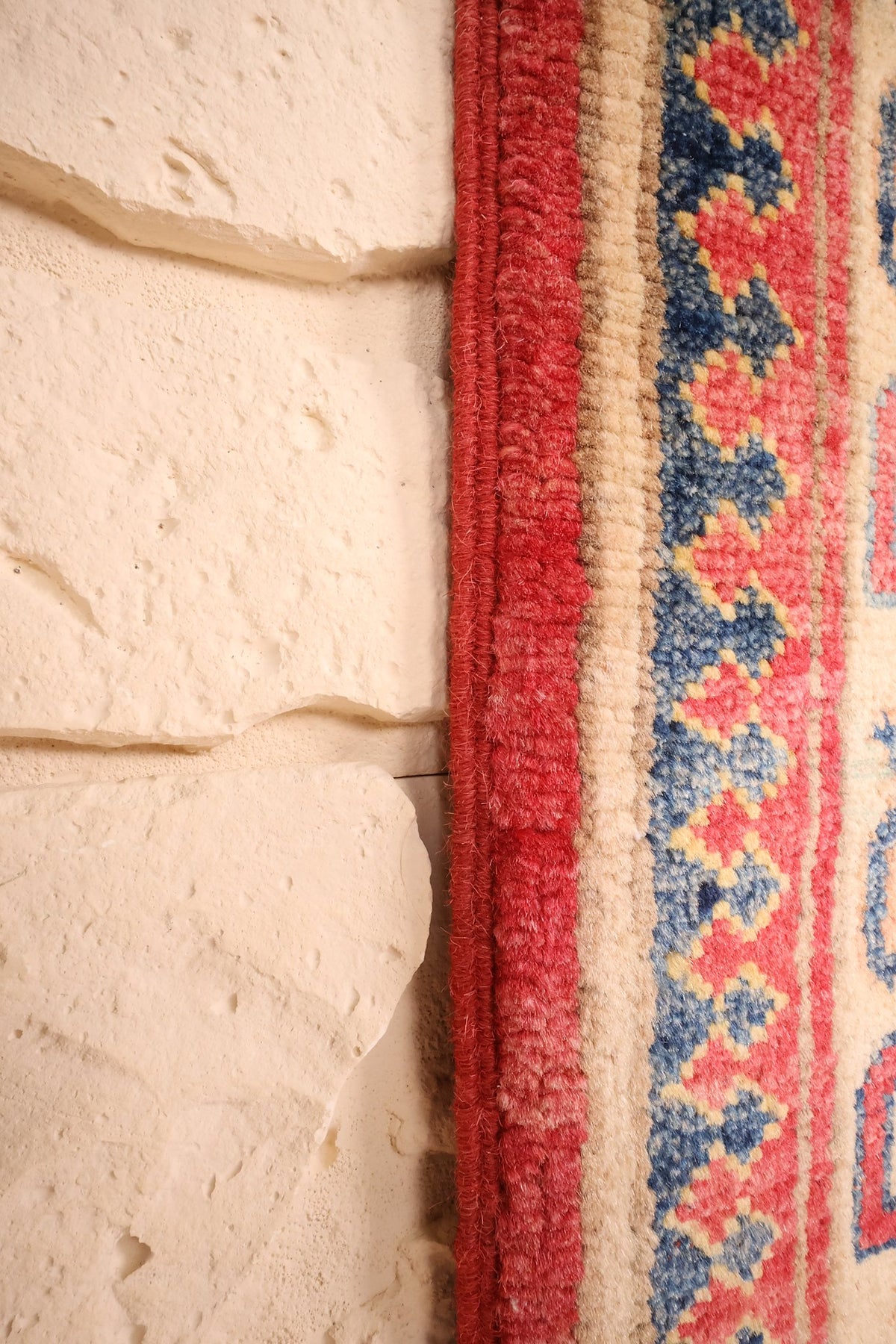 Lisière rouge du tapis Kazak, contre-bordure bleue et jaune en gros plan