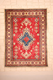Tapis Kazak rouge 145 × 107 cm, vue d'ensemble du médaillon central bleu à crochets