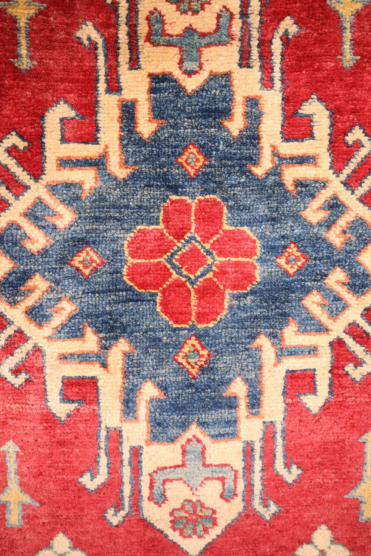 Détail du médaillon bleu et de la rosette rouge du tapis Kazak