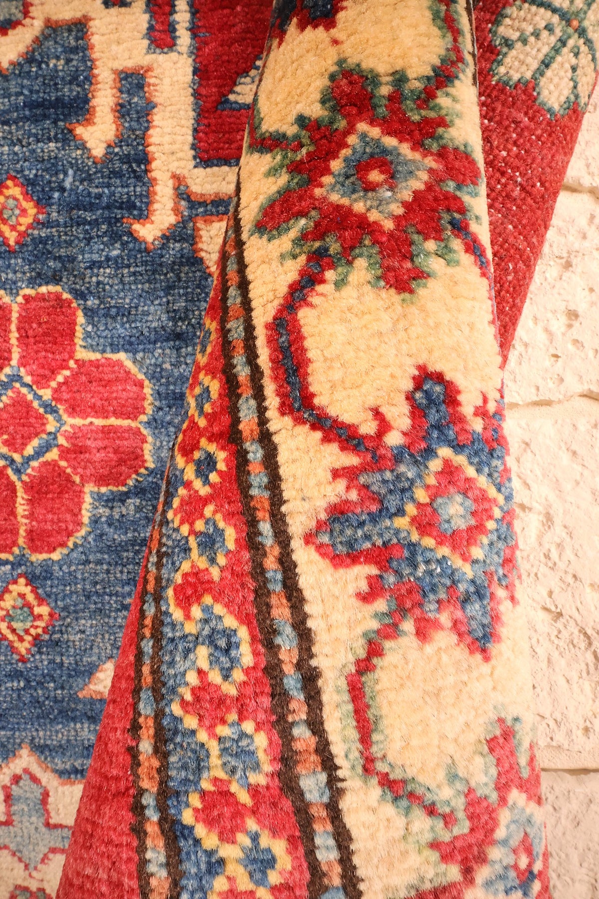 Coin replié du tapis Kazak en laine, épaisseur et motifs ivoire visibles