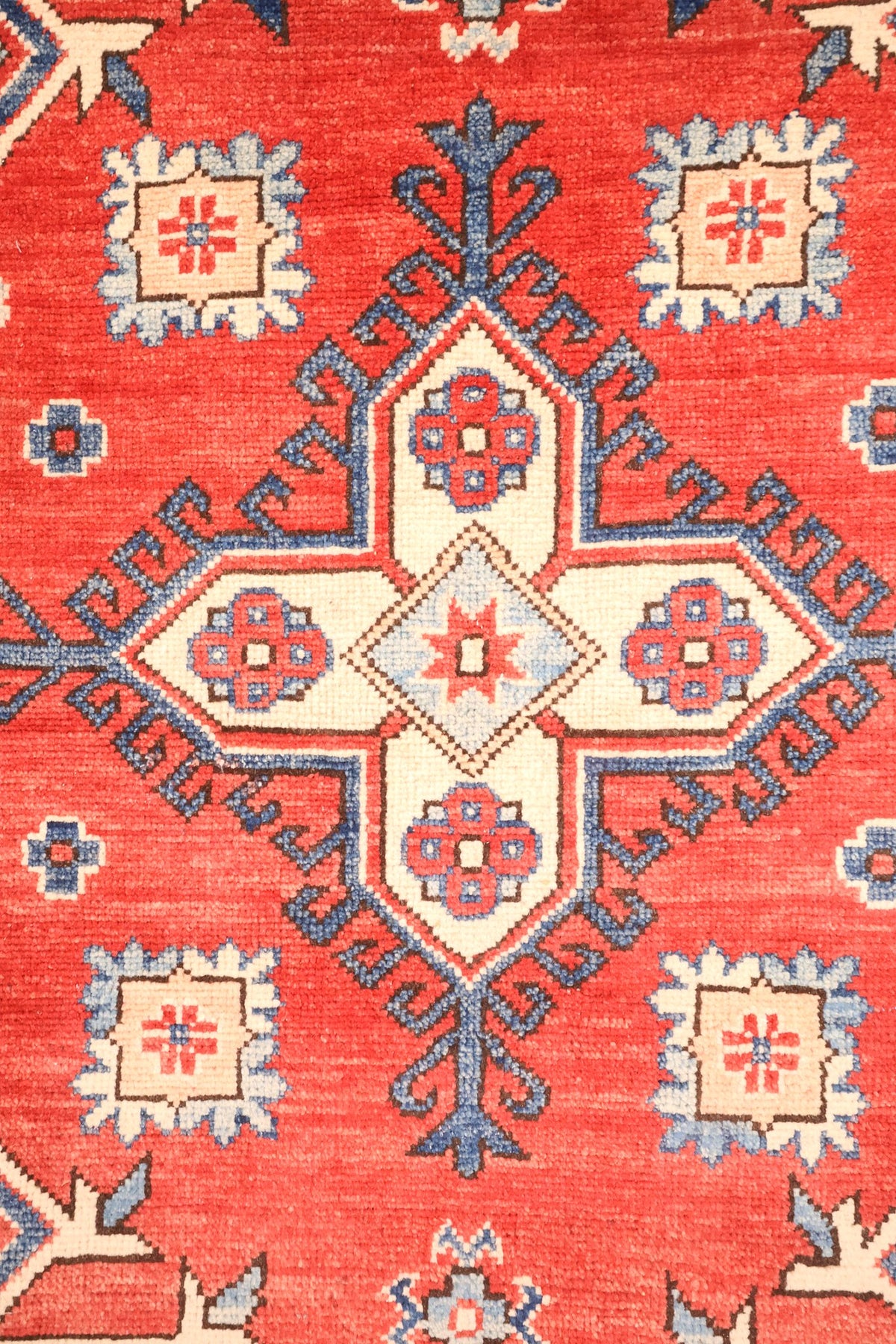 Détail du médaillon cruciforme et des rosettes carrées du tapis Kazak rouge