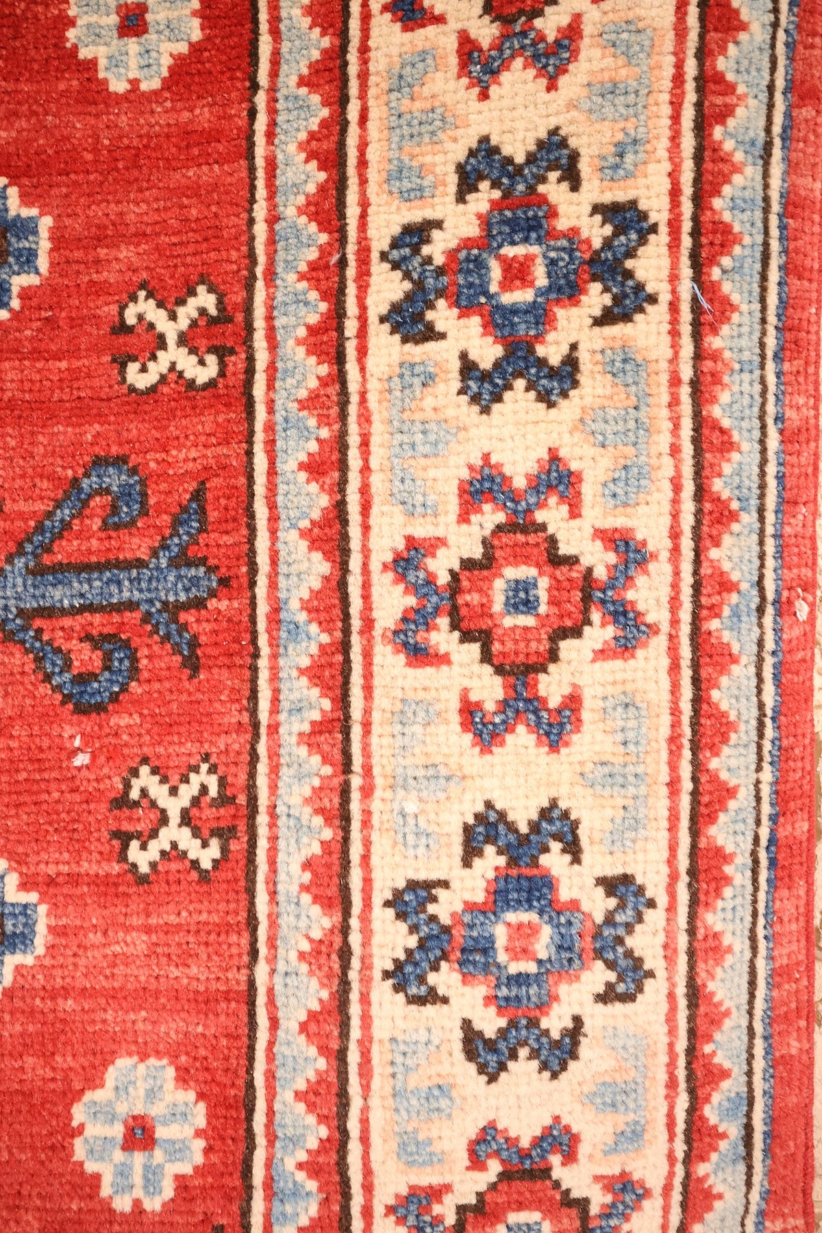 Bordure ivoire à étoiles-rosettes rouges et bleues du tapis Kazak noué main