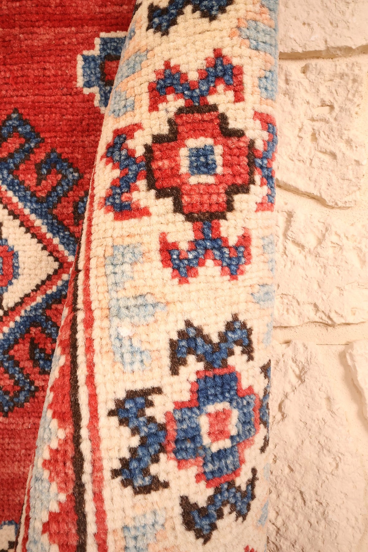 Coin replié du tapis Kazak, bordure ivoire et filets bruns en gros plan