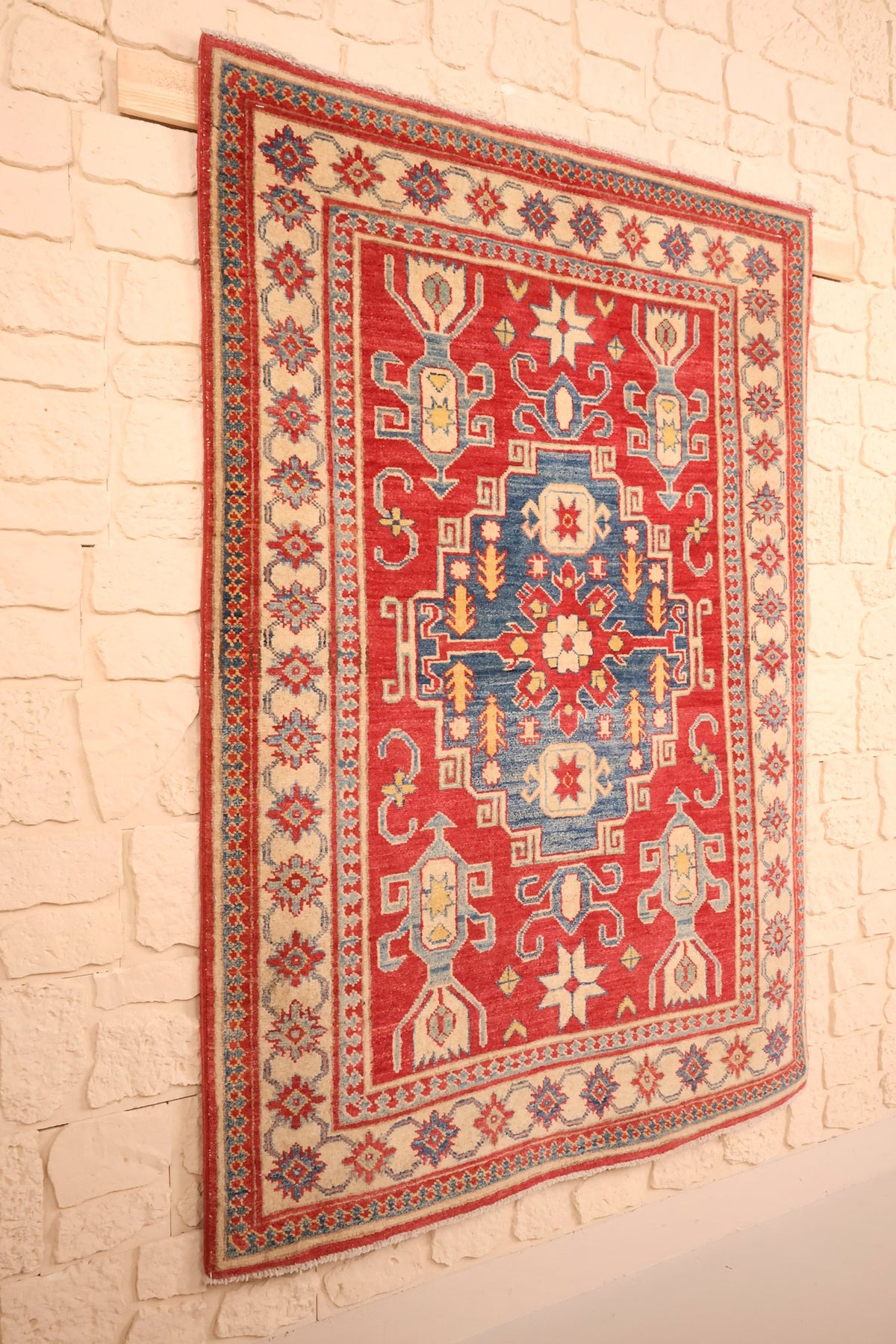 Tapis Kazak rouge et bleu en laine, vue de biais sur le mur