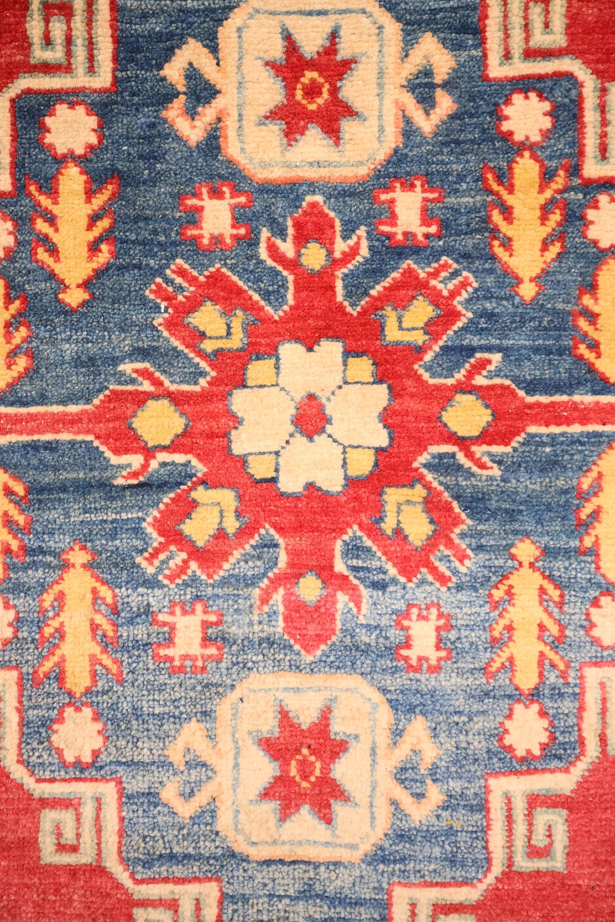 Détail du médaillon anguleux bleu et de sa rosette blanche, tapis Kazak
