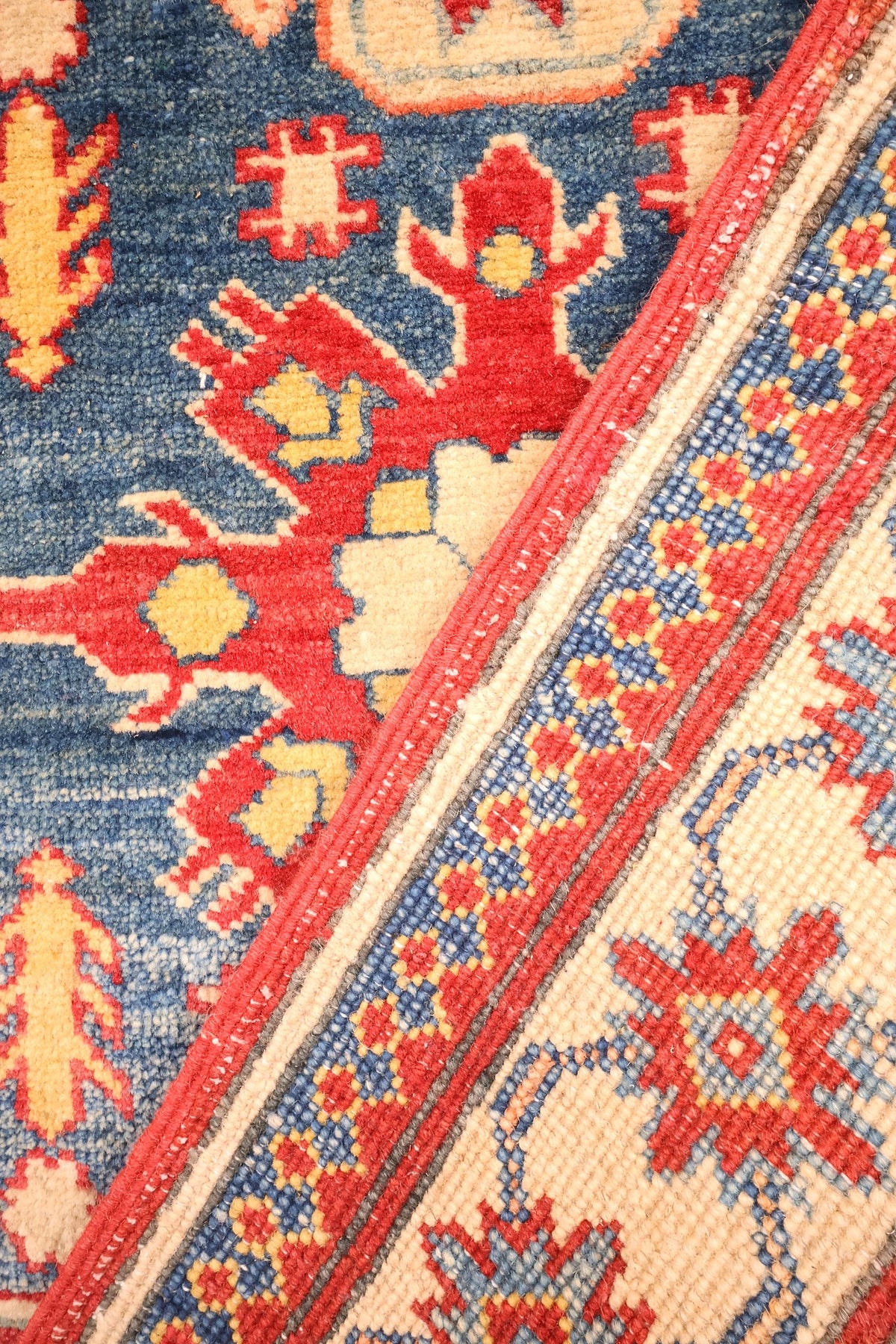 Coin replié du tapis Kazak noué à la main, champ bleu et bordure ivoire
