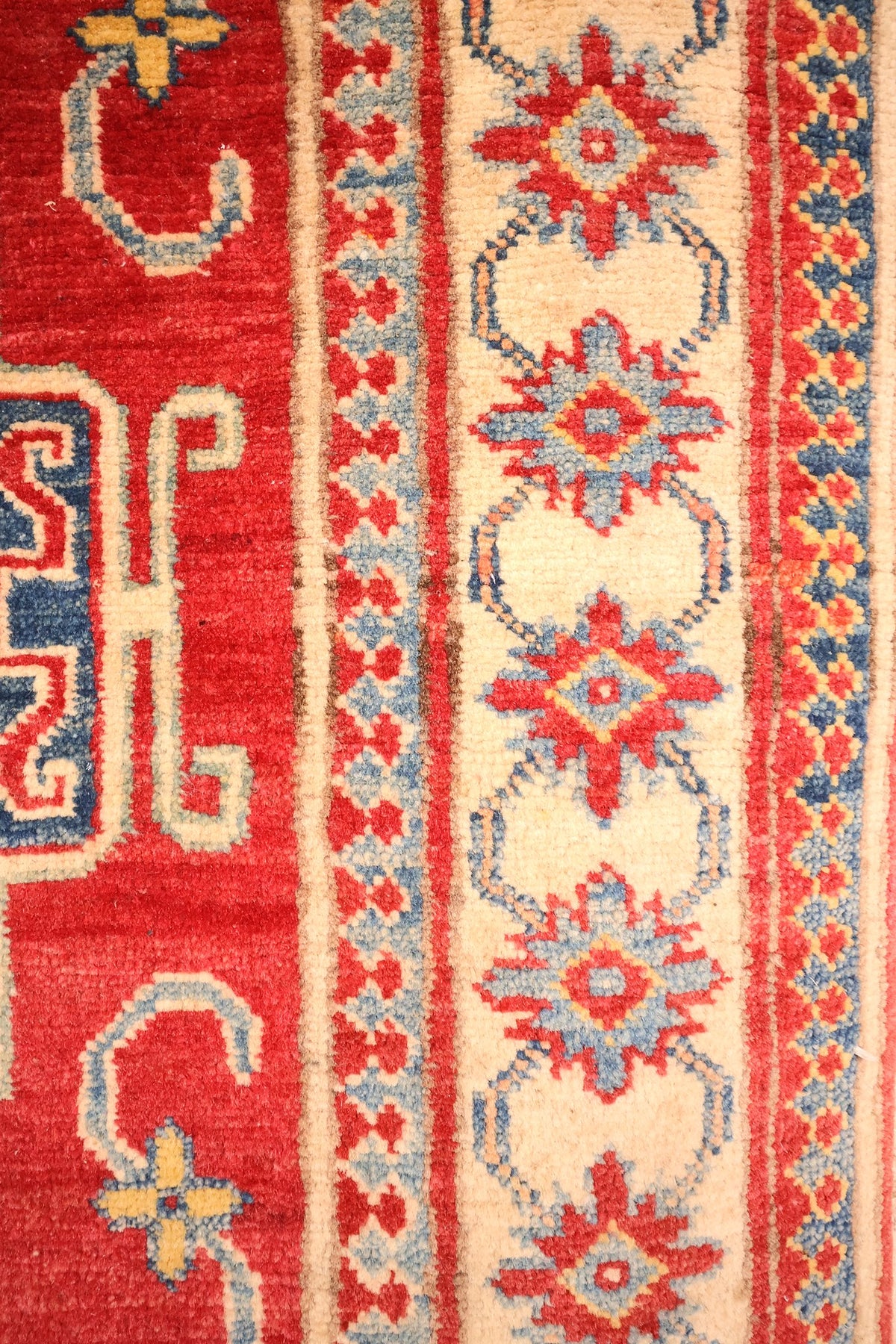 Bordure ivoire à étoiles rouges et bleues du tapis Kazak, contre-bordures