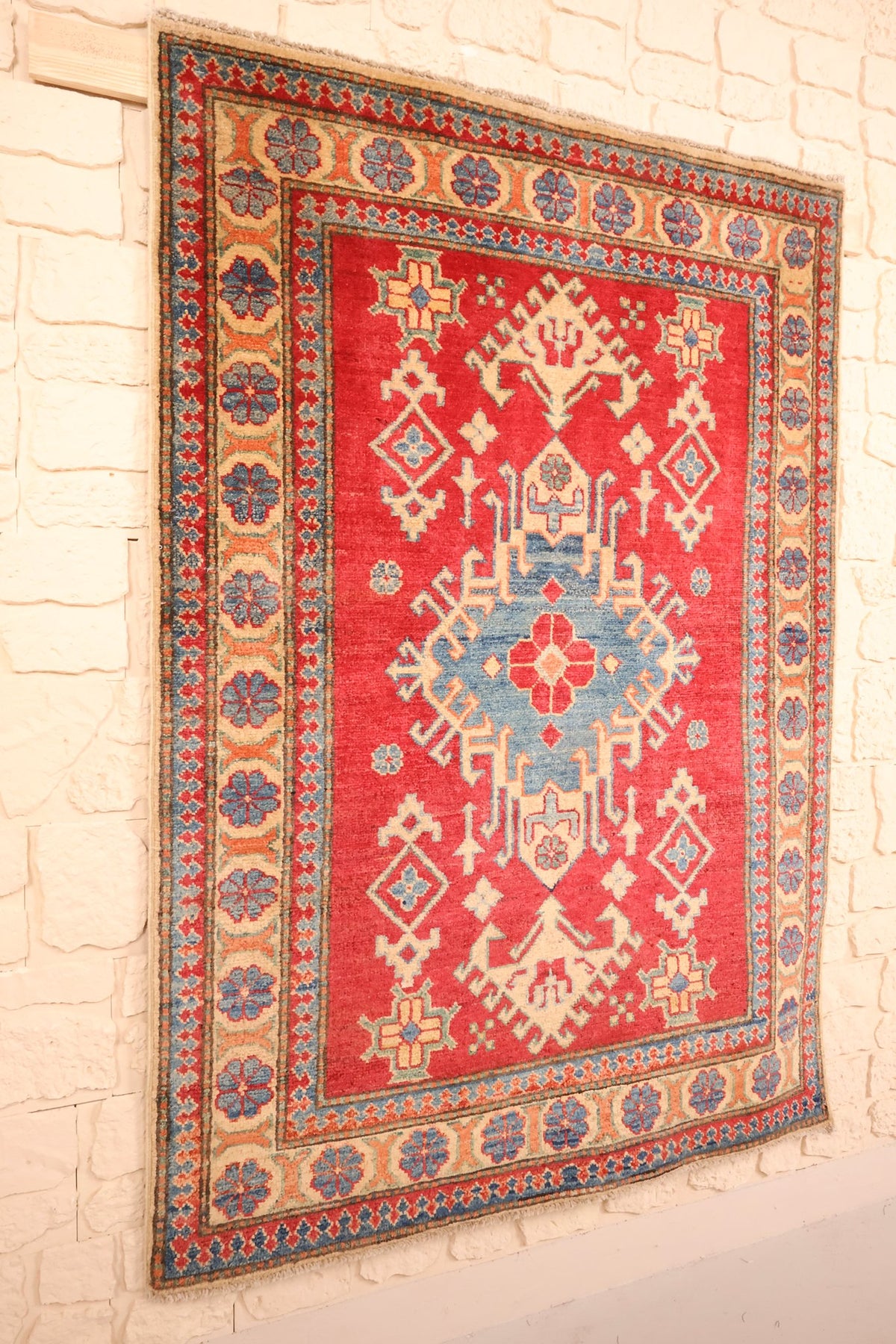 Tapis Kazak en laine noué à la main, vue de biais sur le champ rouge
