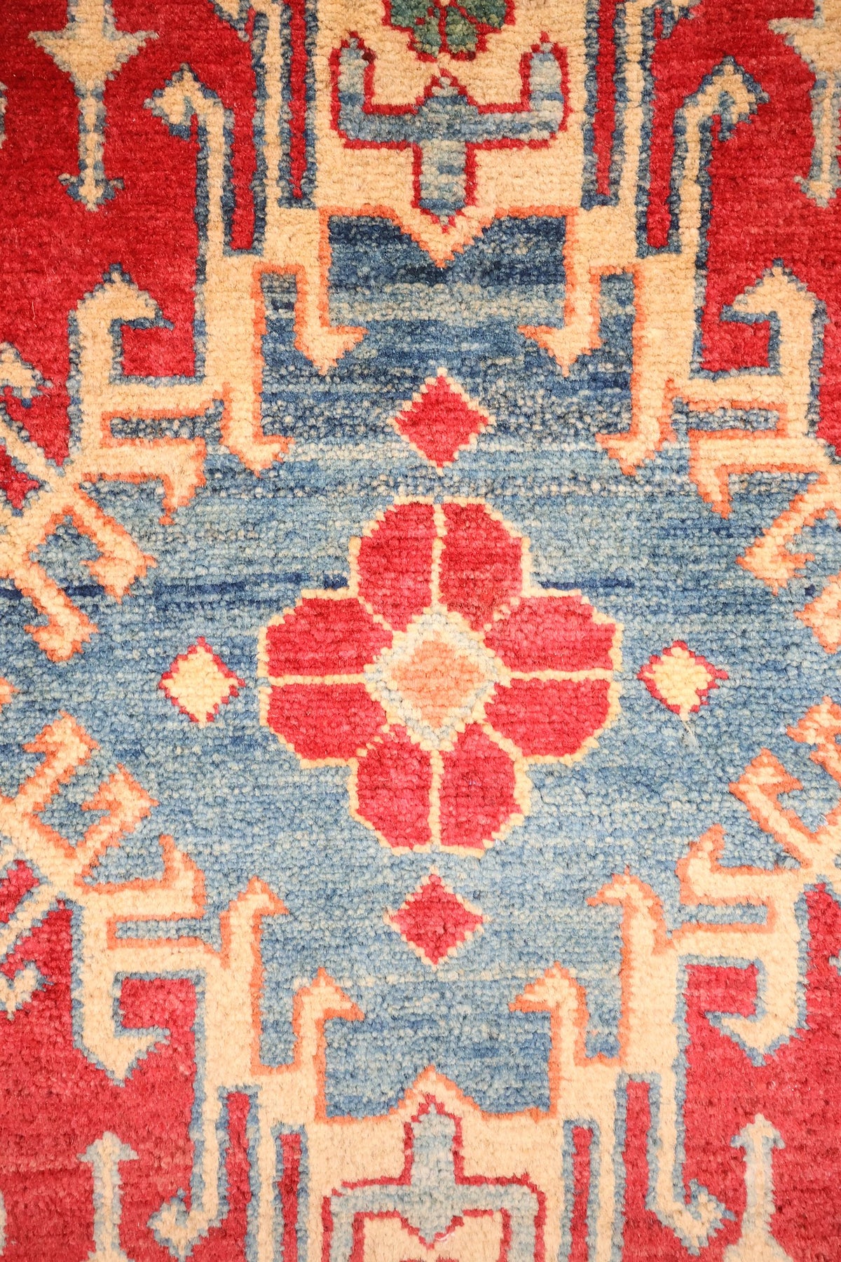 Détail du médaillon bleu clair à rosette rouge du tapis Kazak