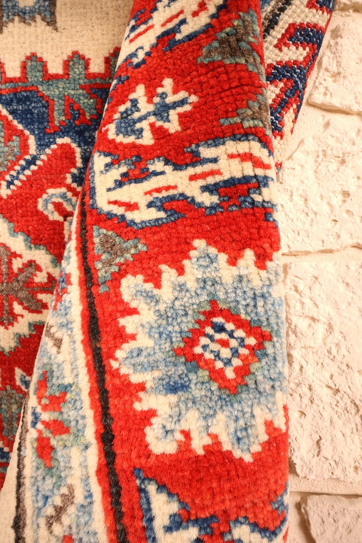 Coin replié du tapis Kazak, laine rouge et bleue aux palmettes crochetées