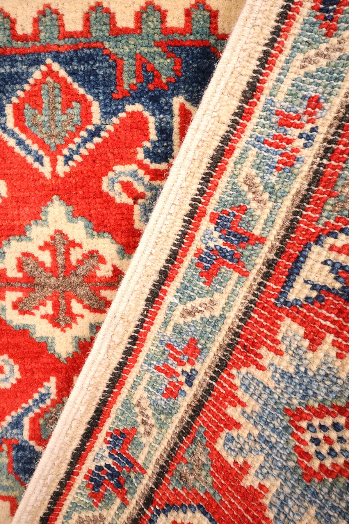 Envers du tapis Kazak en laine, nœuds serrés et motifs rouges visibles
