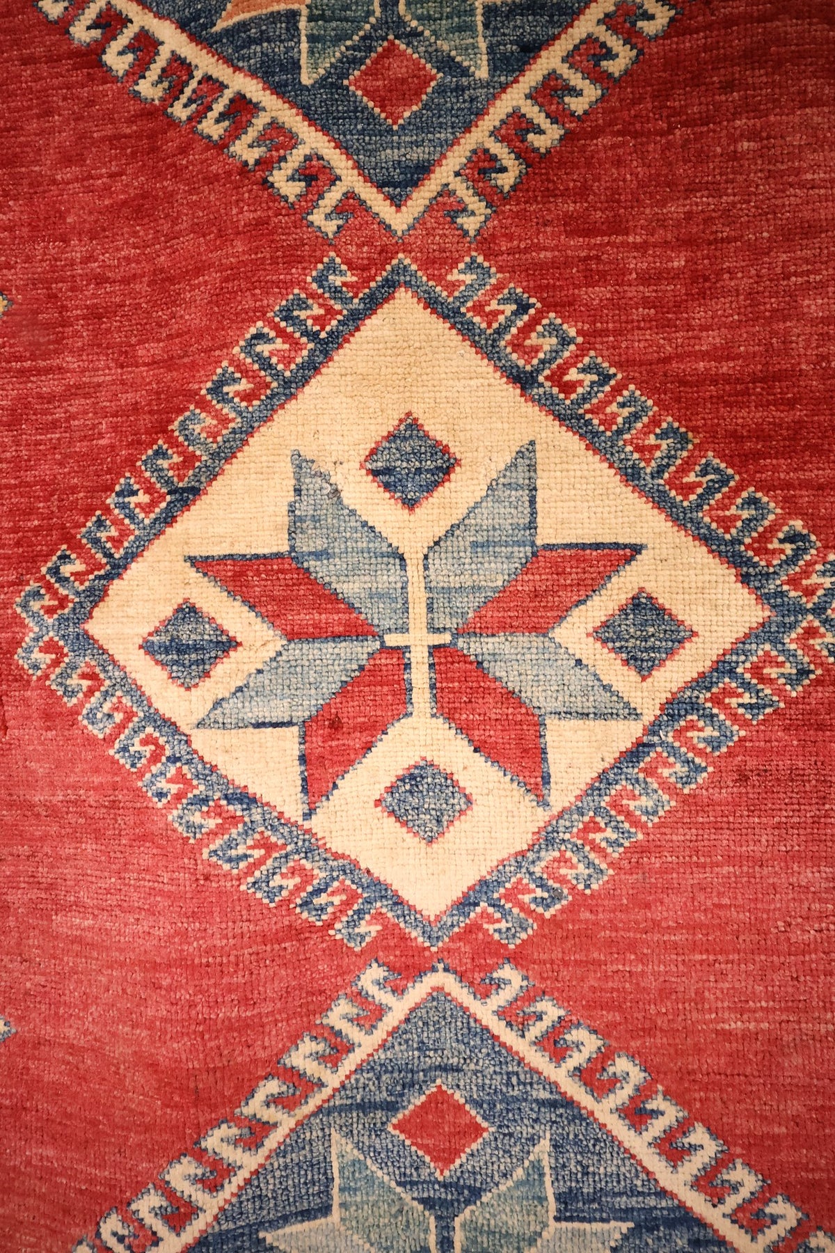 Détail du médaillon beige à étoile à huit branches du tapis Kazak rouge