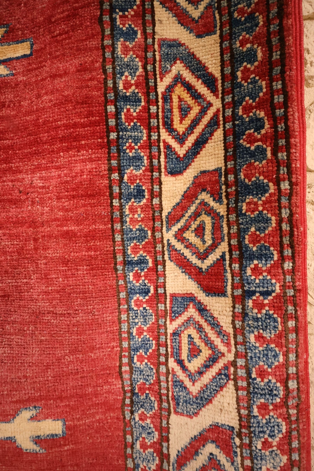 Bordure beige à losanges bleus et contre-bordures à feuilles du tapis Kazak
