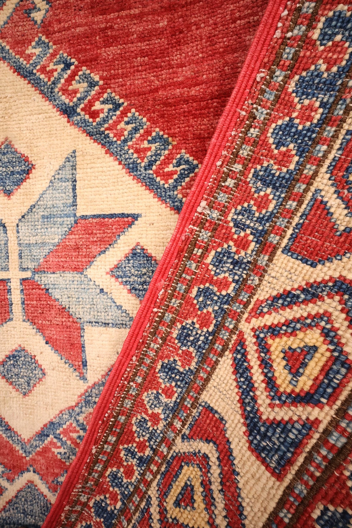 Coin replié du tapis Kazak en laine, médaillon beige et bordure côte à côte