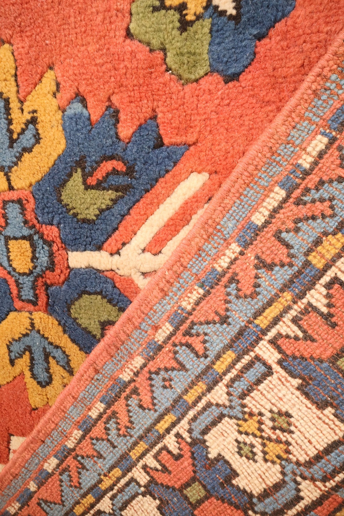 Coin replié du tapis Indigo rouge, passage du champ aux filets à damier