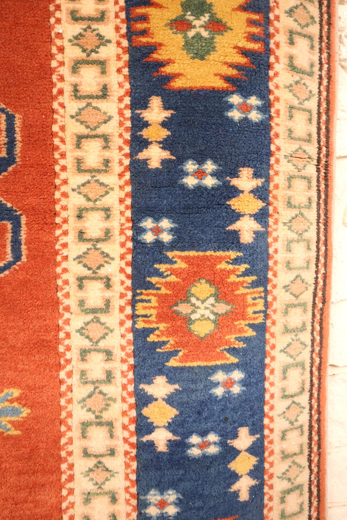 Bordure bleue du tapis Konya, cartouches rouges et jaunes et losanges verts