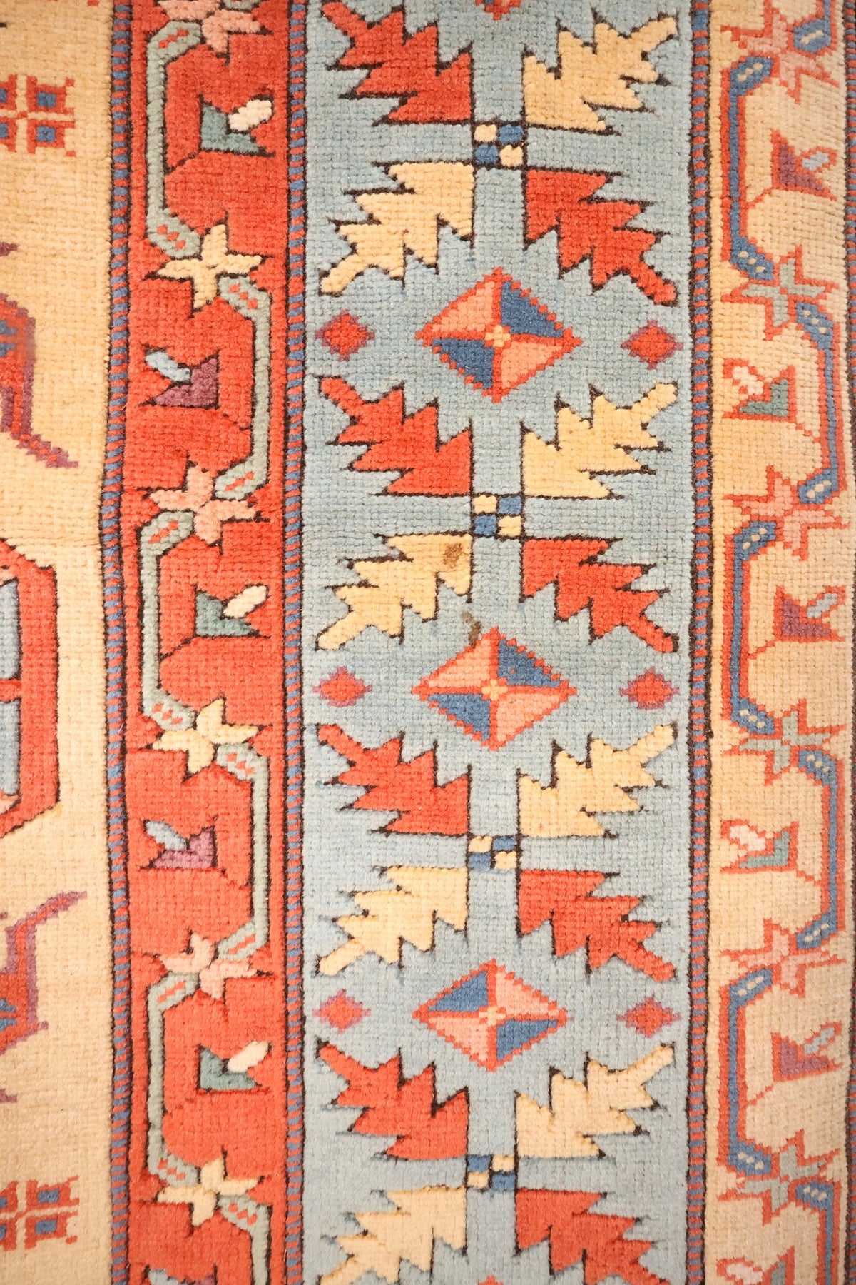 Bordure bleu-gris du tapis Konya, feuilles dentelées rouges et beiges