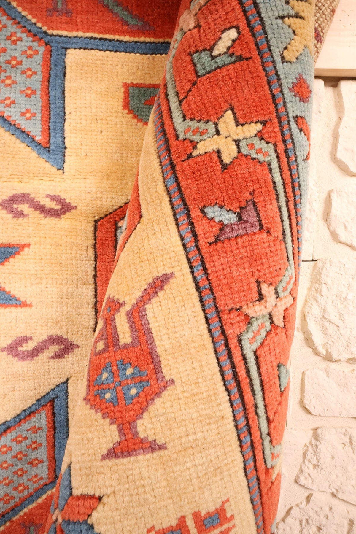 Pli du tapis Konya beige et rouge montrant un motif floral stylisé en bordure