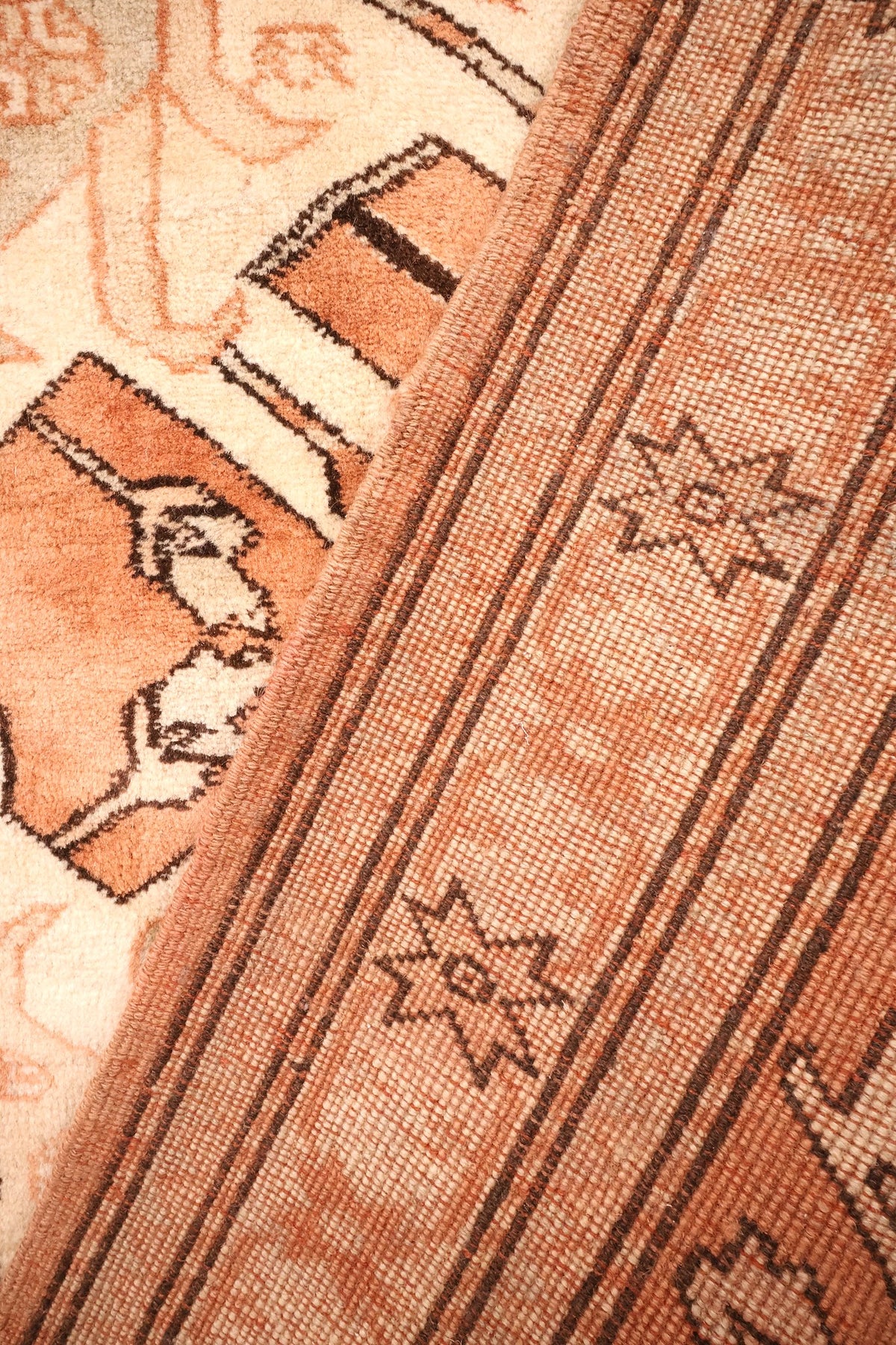 Coin replié du tapis Kula, envers et nœuds visibles sous la bordure étoilée
