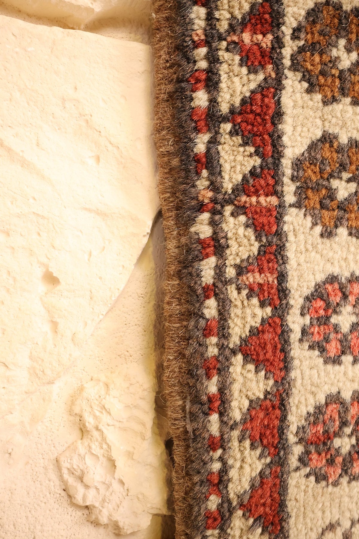 Lisière du tapis Melas, contre-bordure ivoire à rosettes rondes rouges et brunes