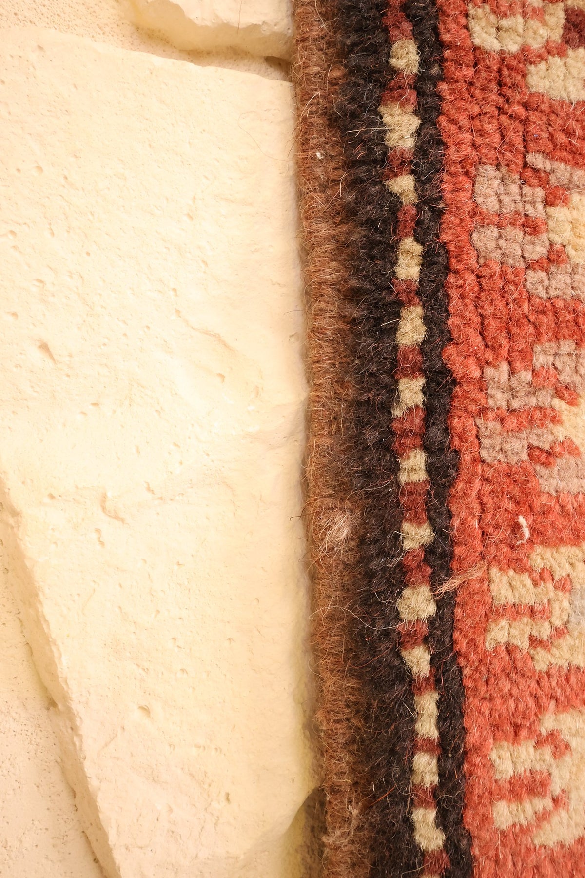 Lisière du tapis Melas rouge et beige, finition latérale en laine vue de près