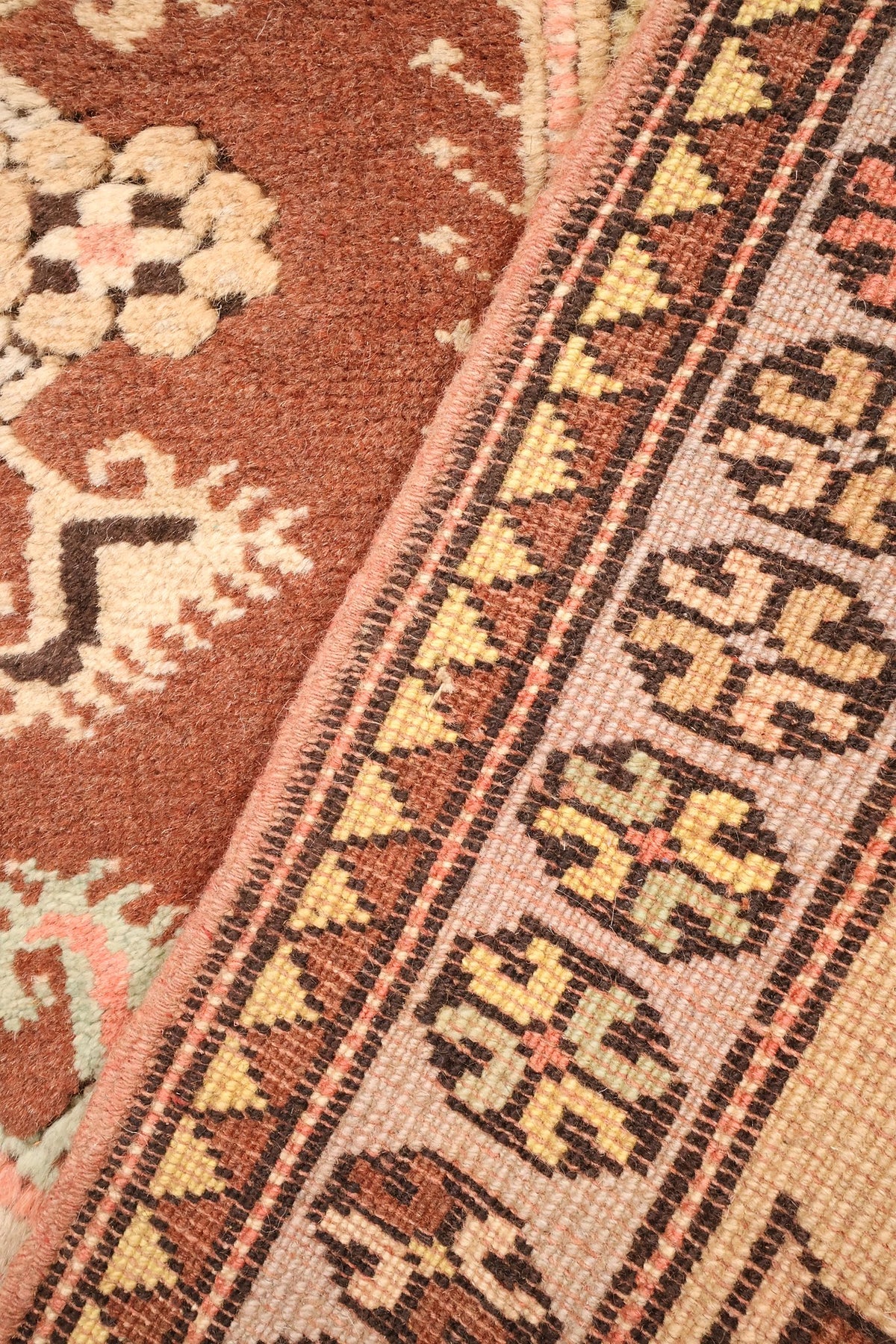 Envers du tapis Melas en laine, nœuds et rosettes de bordure visibles
