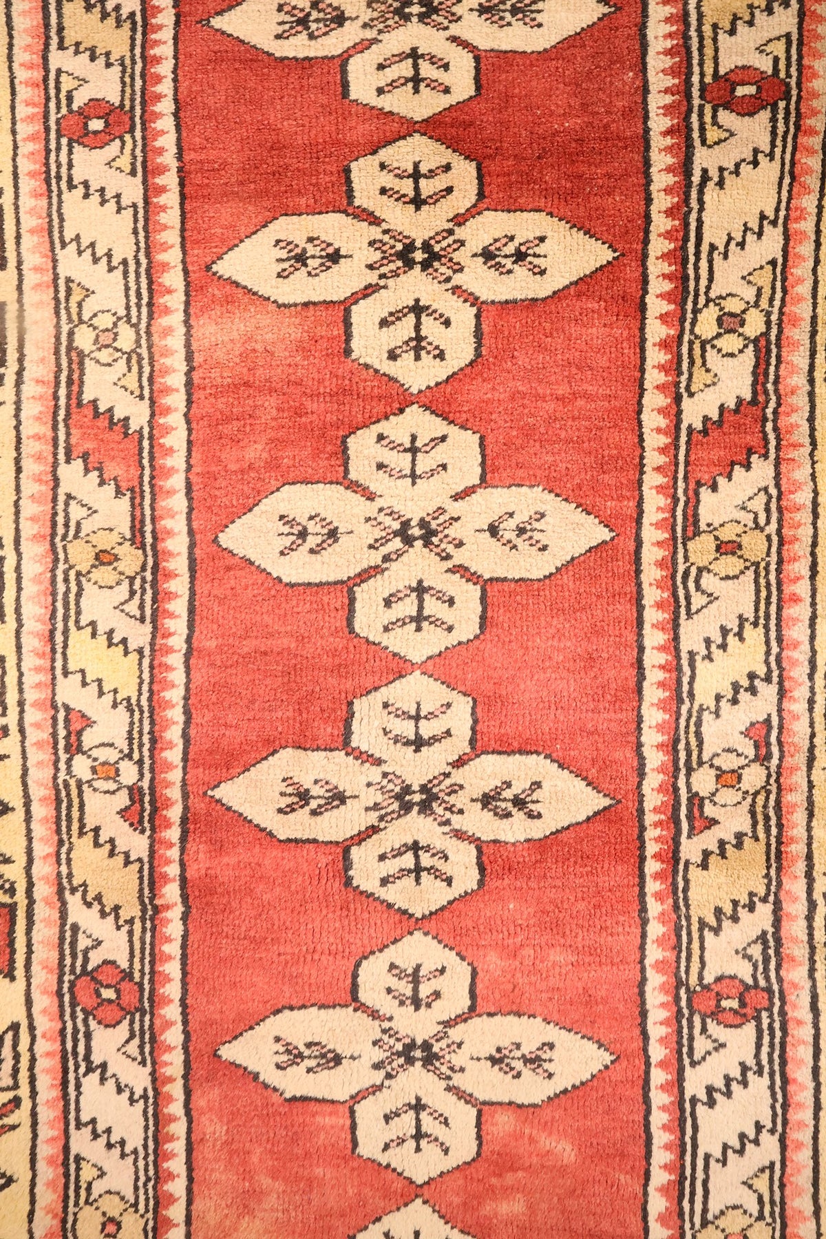Détail de la colonne de médaillons crucifères beiges sur champ rouge brique, tapis Melas