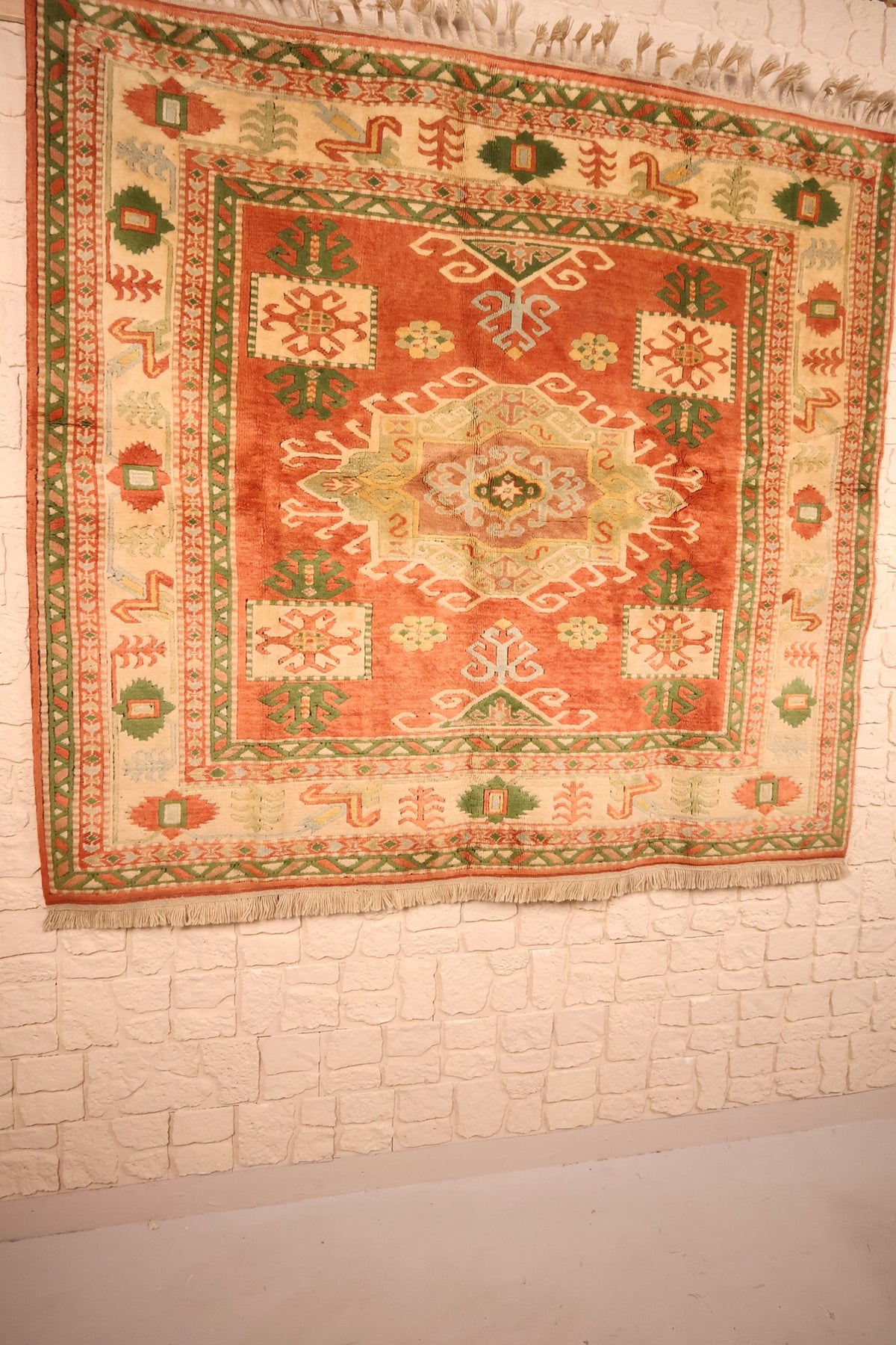 Tapis Melas en laine noué main, vue de biais sur le champ orange-brique
