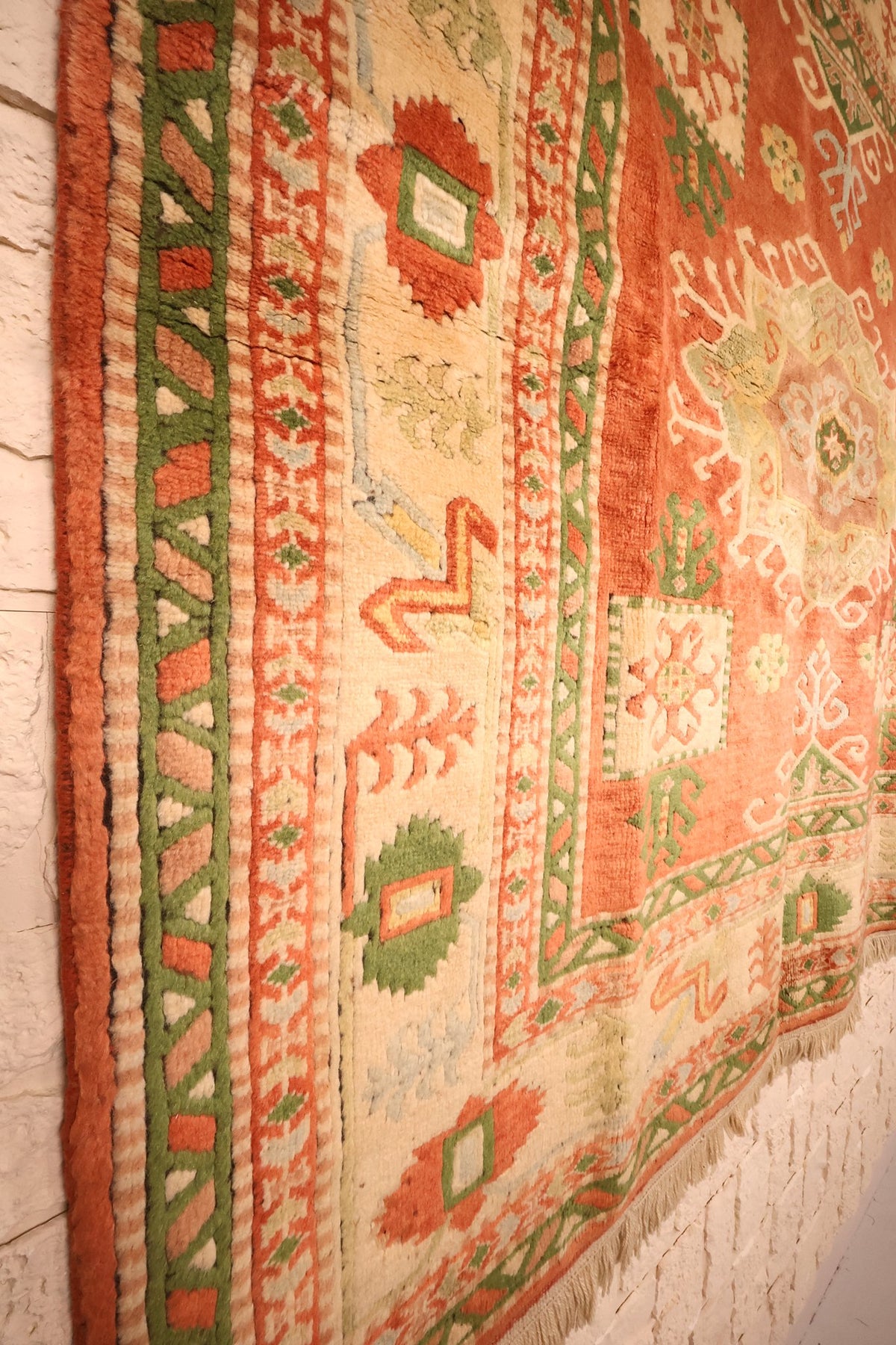 Vue oblique des bordures du tapis Melas, cartouches ivoire et galons verts