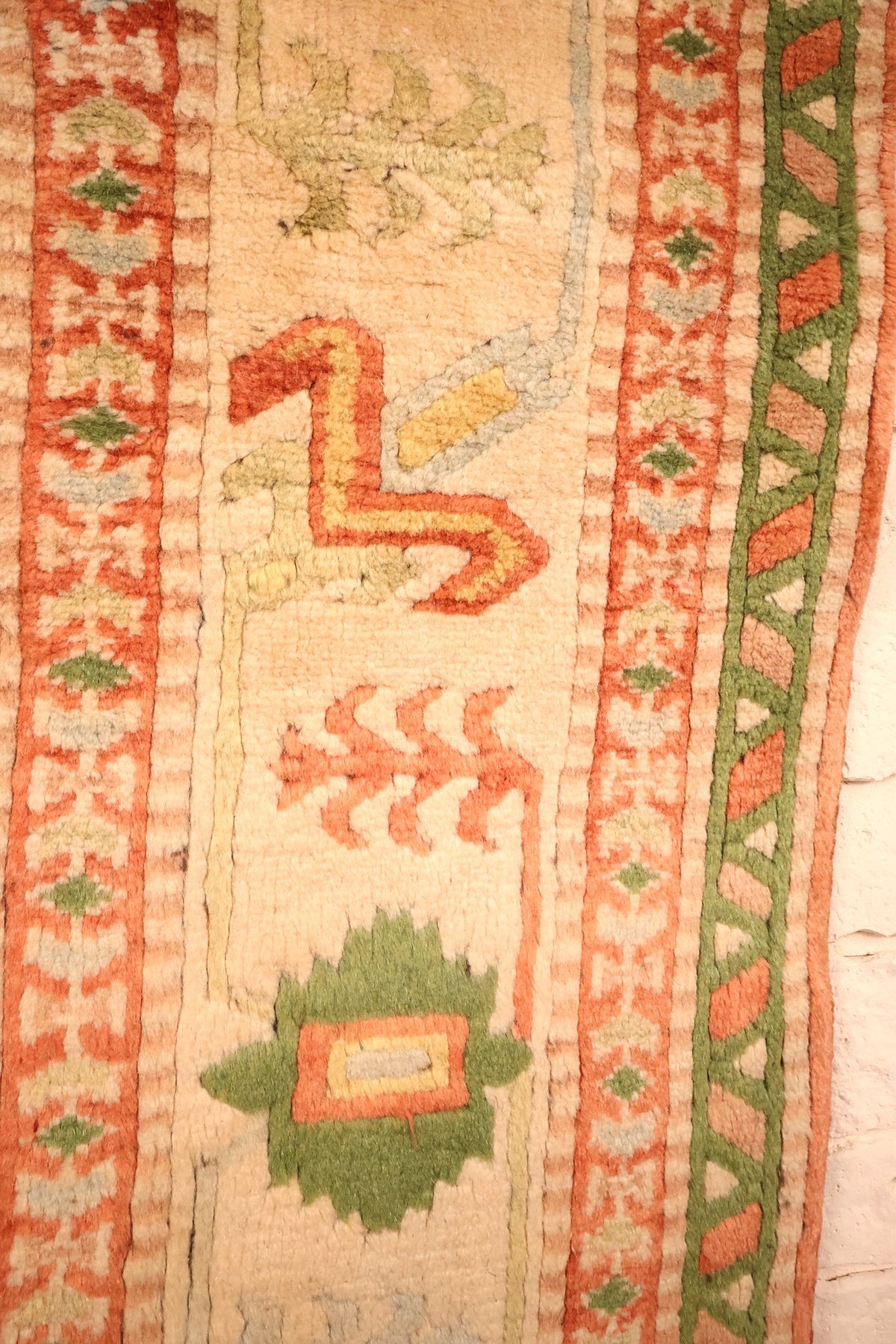 Bordure ivoire du tapis Melas, motifs en S et palmette verte en gros plan