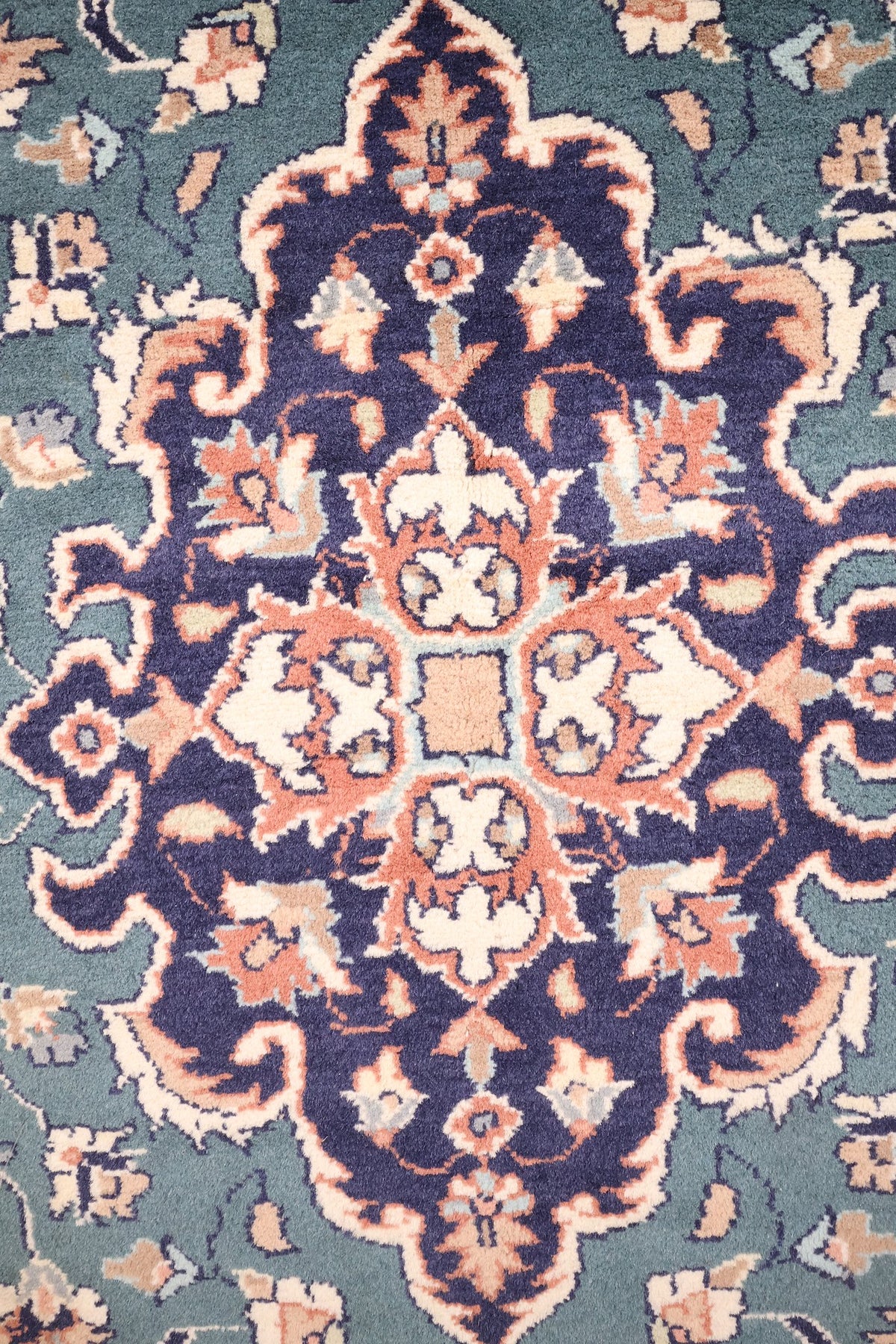 Détail du médaillon bleu nuit à contour découpé du tapis Pendjab, motifs roses et ivoire