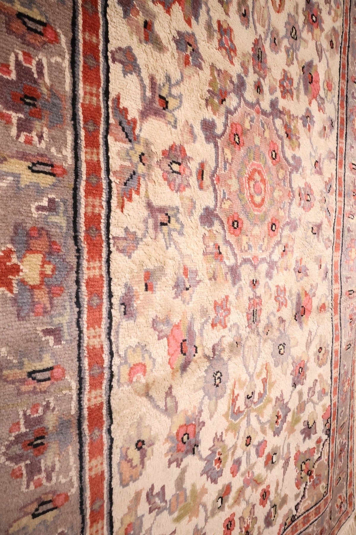 Rinceaux et fleurs mauves du champ ivoire, près de la bordure du tapis PLS