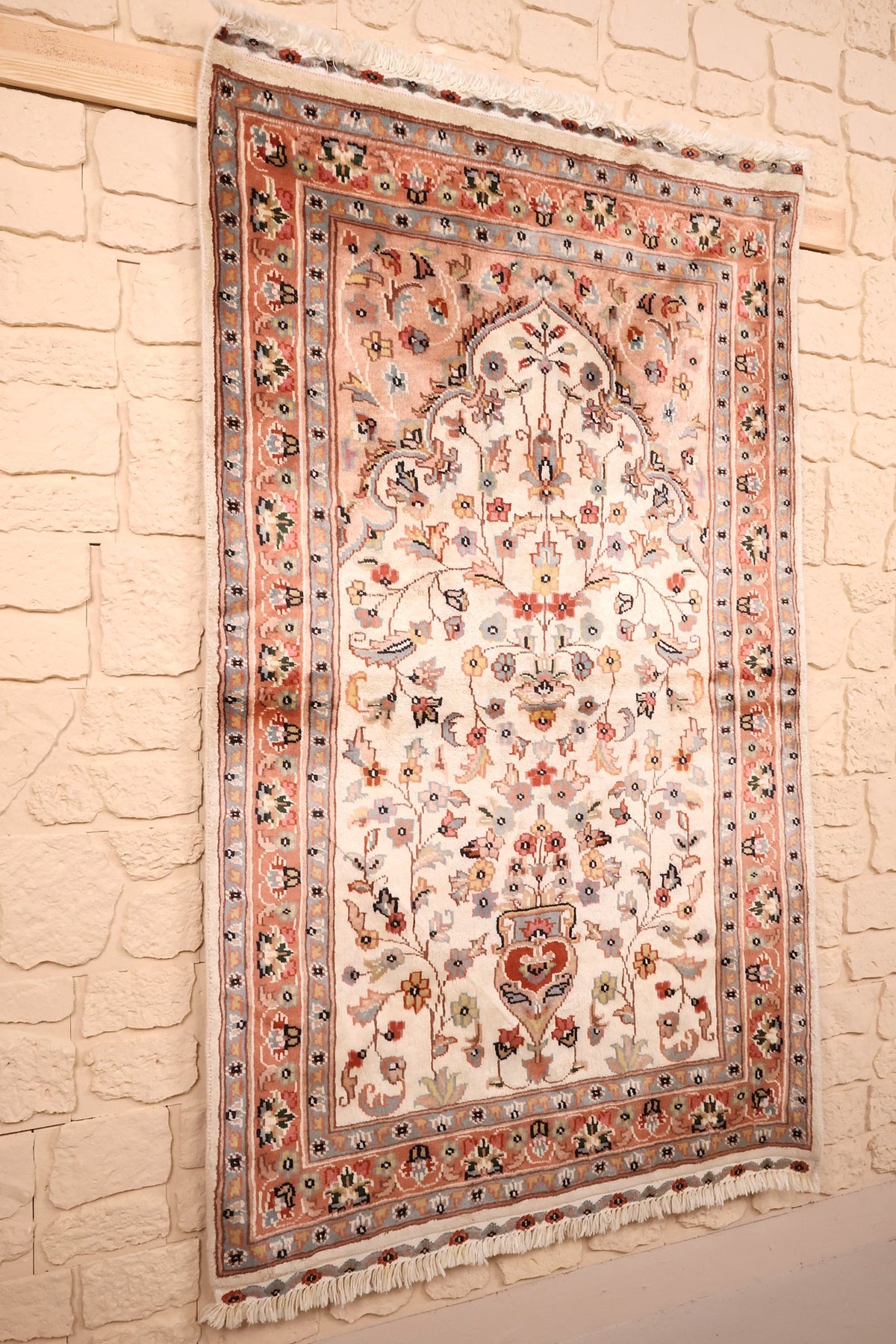 Tapis PLS beige et orange vu de biais, décor floral en semis et arche centrale