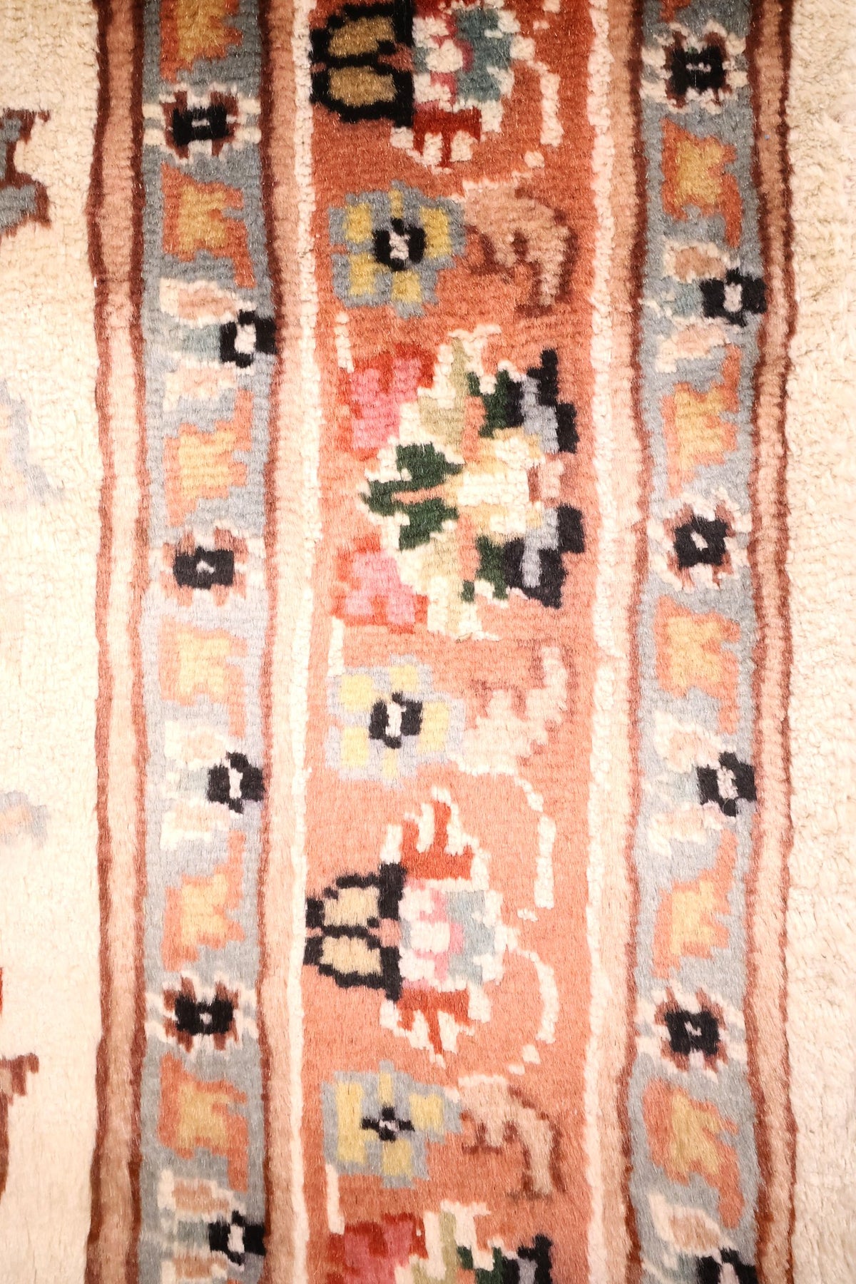 Bordure saumon à rinceaux fleuris et contre-bordures gris-bleu du tapis PLS