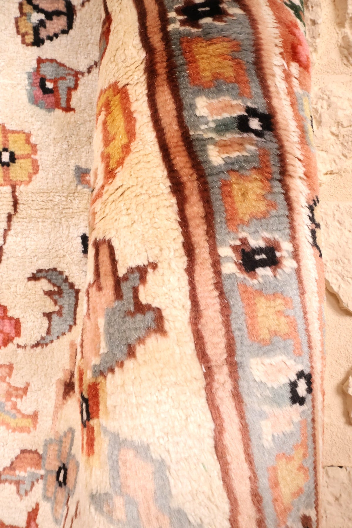 Coin replié du tapis PLS beige, épaisseur et filets bruns de la bordure