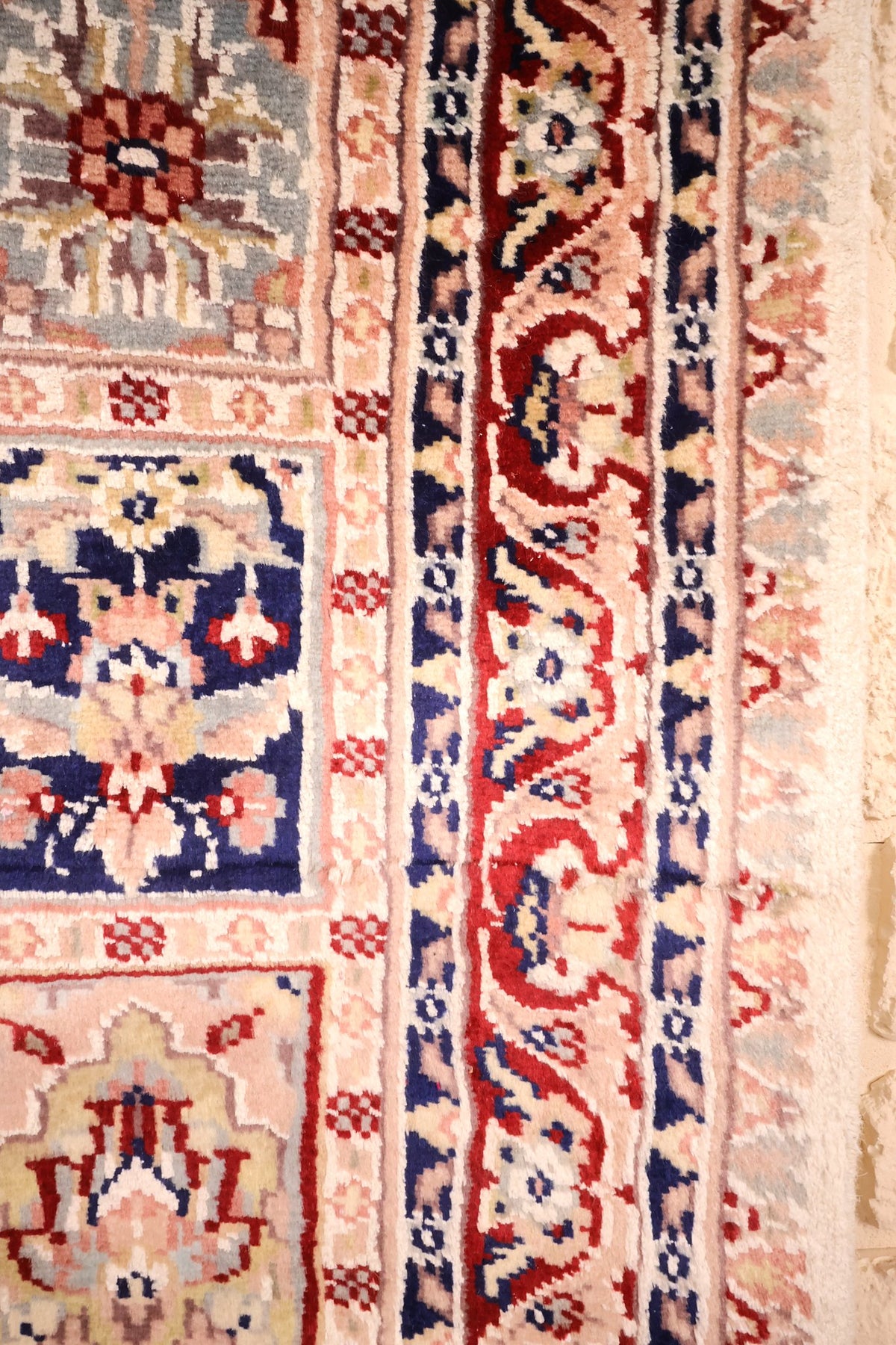 Bordure rouge à rinceaux floraux ivoire et contre-bordures bleu nuit du tapis PLS