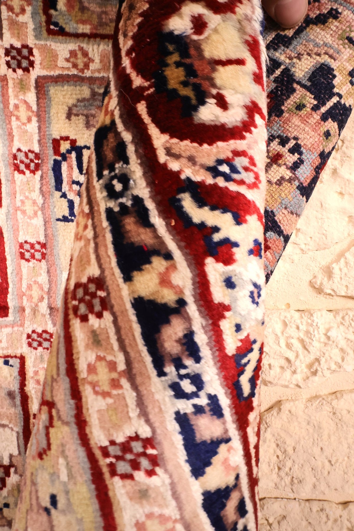 Pli du tapis PLS montrant l'épaisseur et les tons rouge, bleu marine et ivoire
