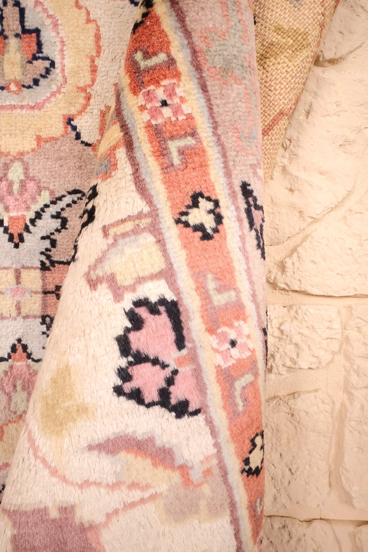 Coin replié du tapis PLS beige, épaisseur et bordure orangée visibles