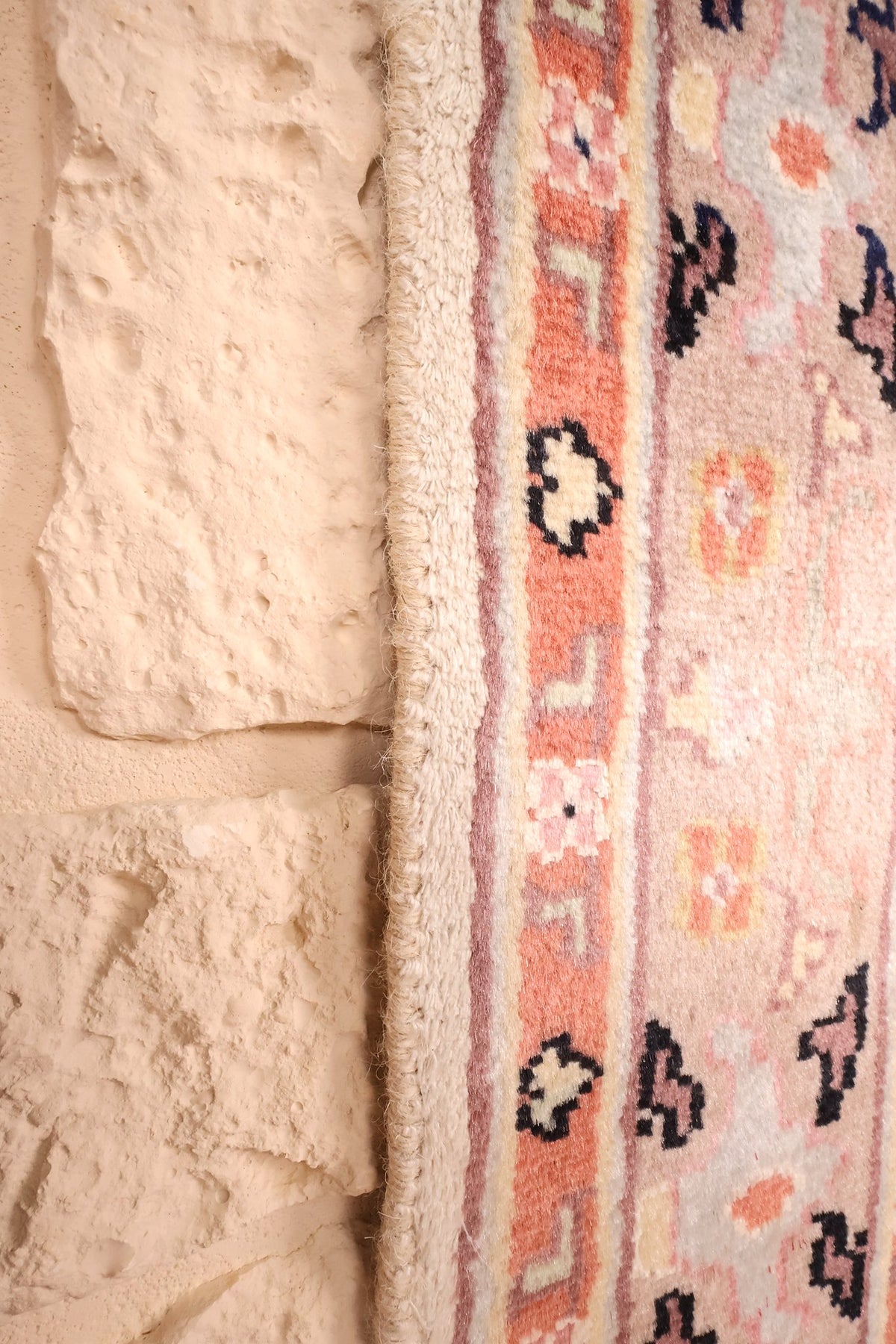 Lisière du tapis PLS en laine naturelle, bord beige le long de la bordure rose