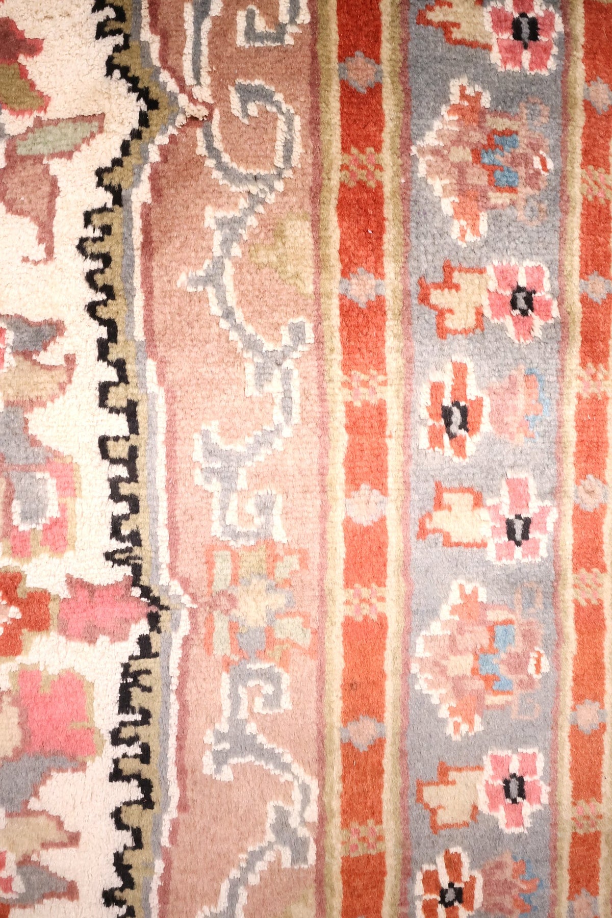 Bordure gris-bleu à fleurs roses et bandes rouge brique du tapis PLS beige