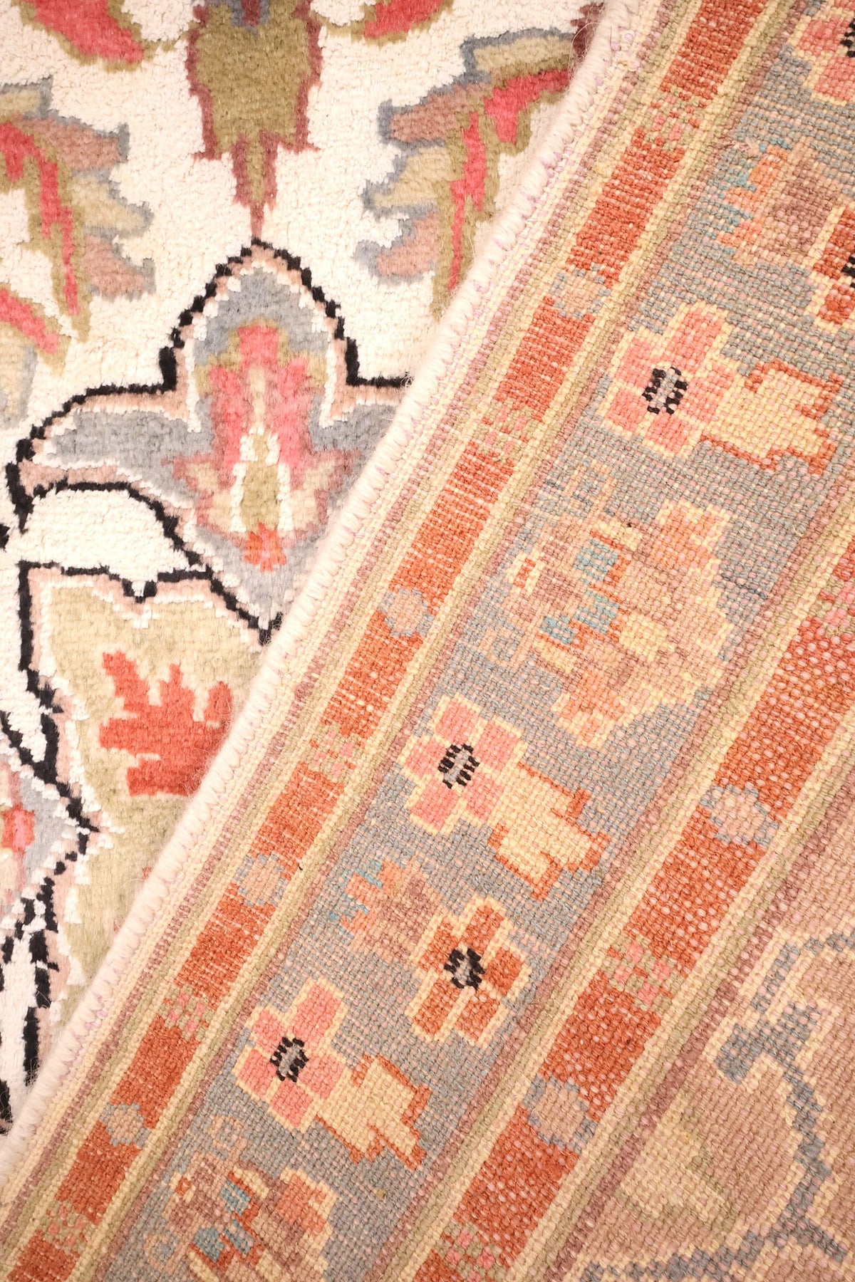 Coin replié du tapis PLS, nœuds de l'envers et bordure fleurie visibles