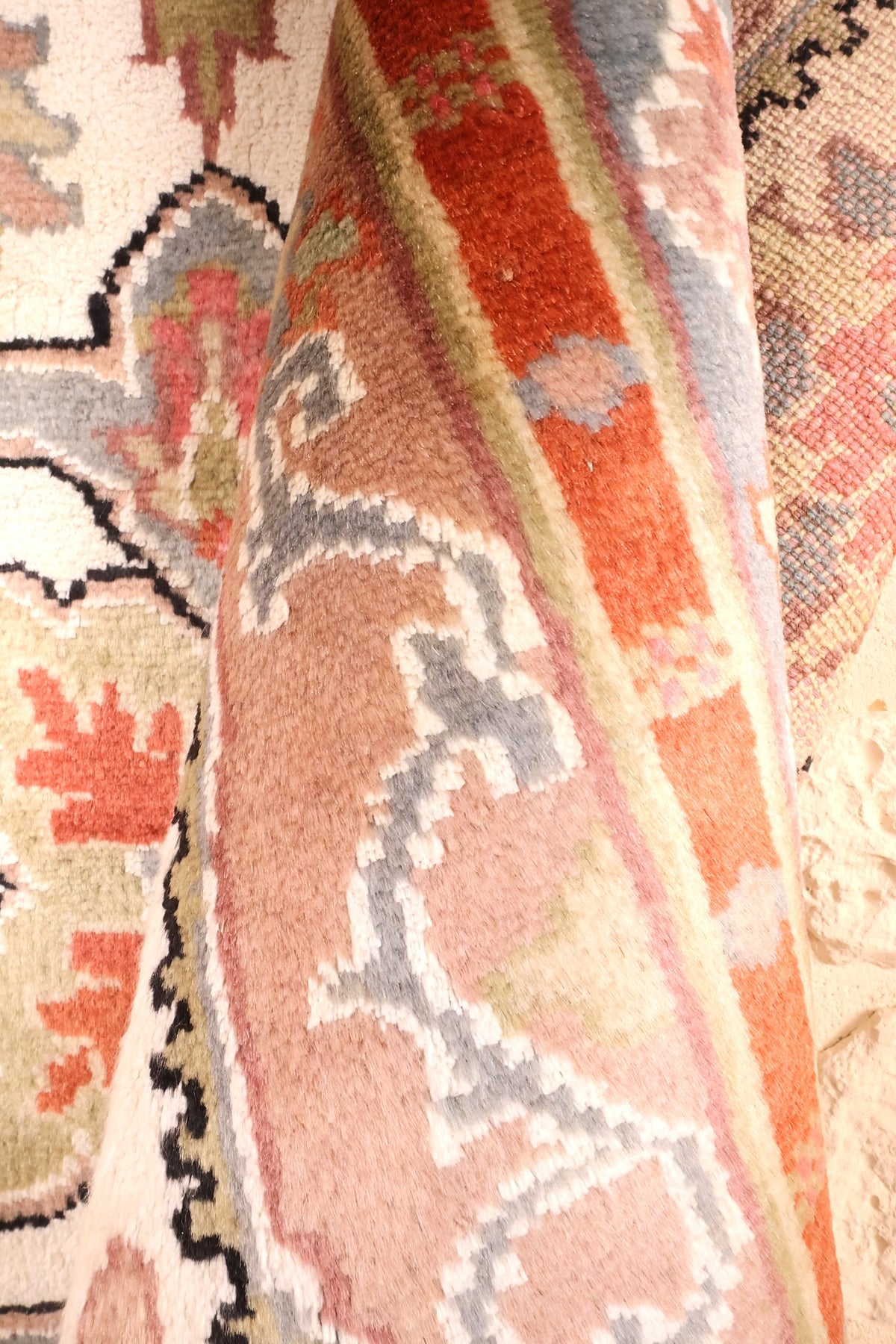 Tapis PLS noué à la main, repli montrant les rinceaux rose-beige de la bordure
