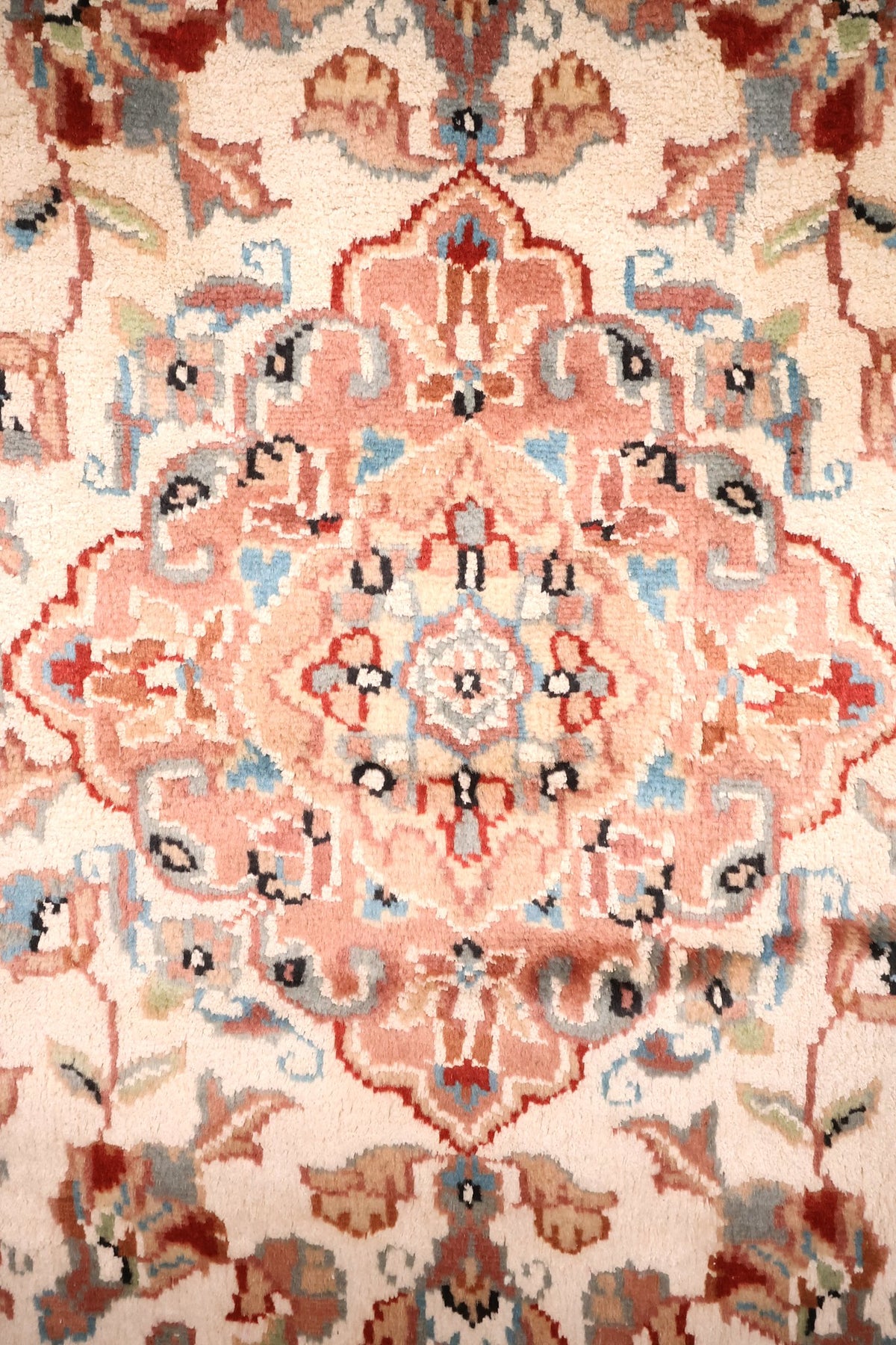 Détail du médaillon losangé rose saumon et des rinceaux bleus du tapis PLS