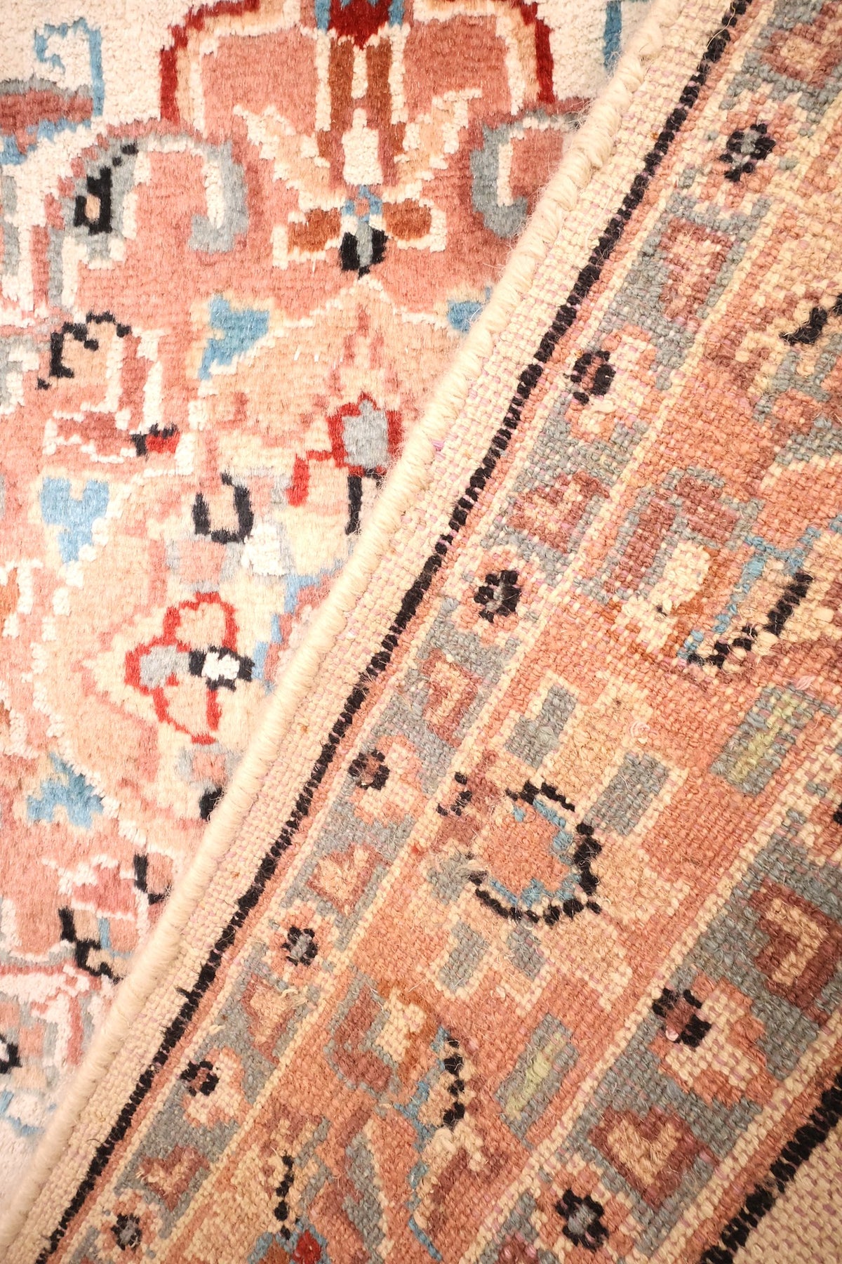 Coin replié du tapis PLS, nœuds du dos et bordure saumon côte à côte