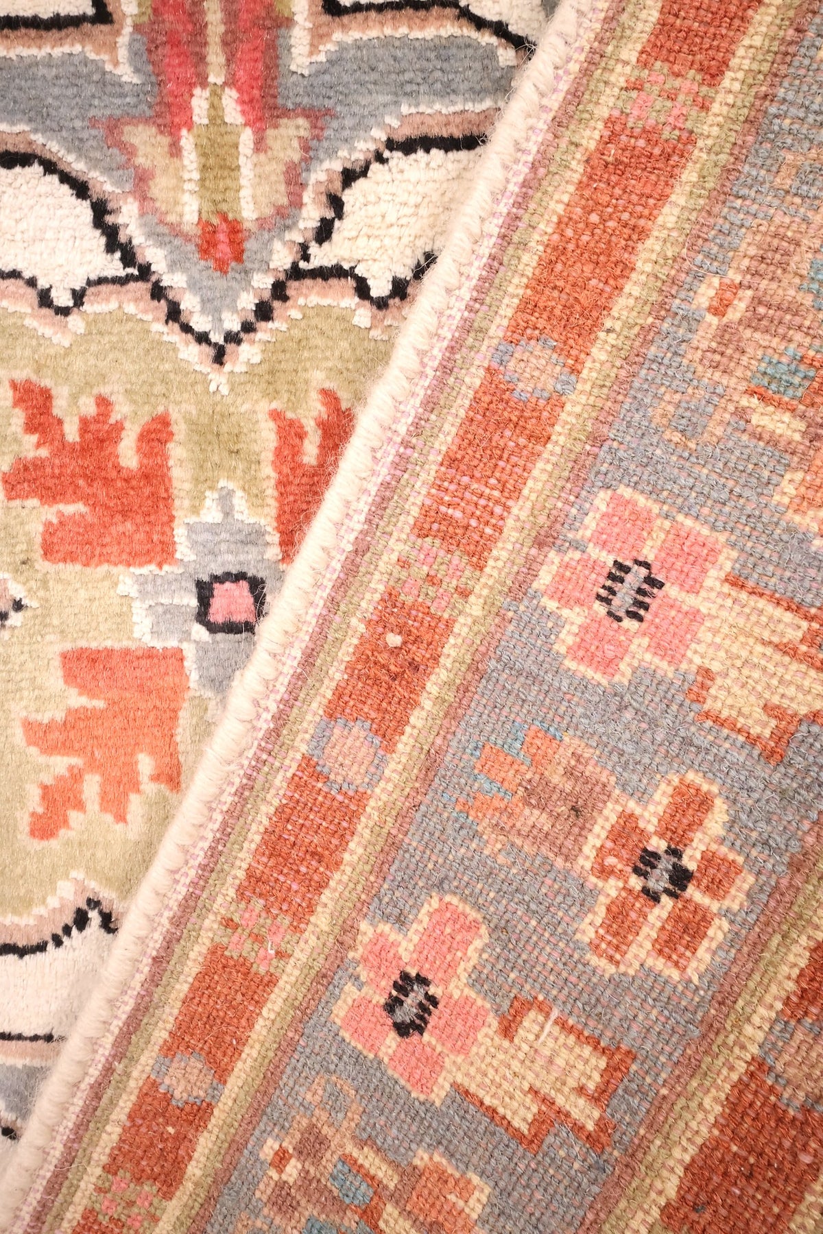 Envers du tapis PLS noué à la main, nœuds et bordure fleurie rose visibles