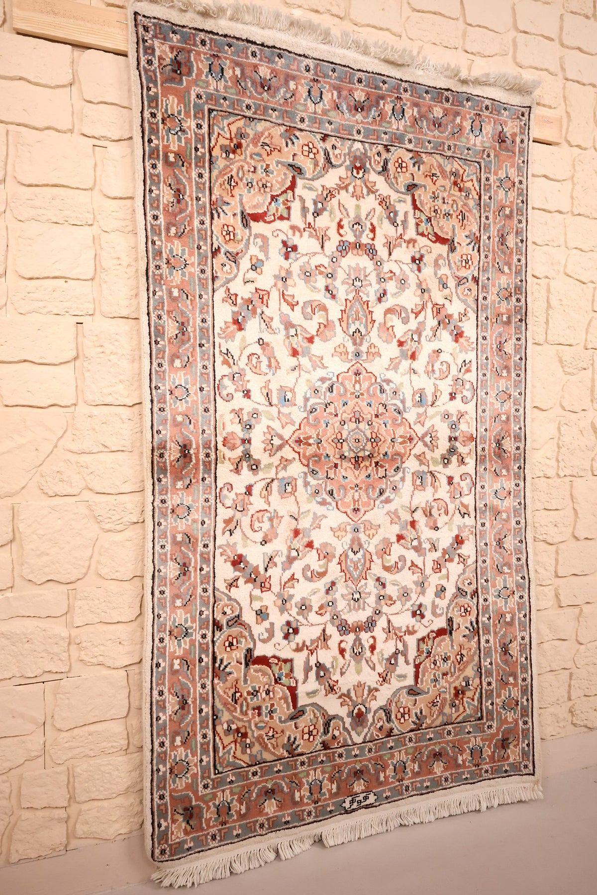 Tapis PLS rectangulaire beige et rose vu de biais, franges blanches aux extrémités