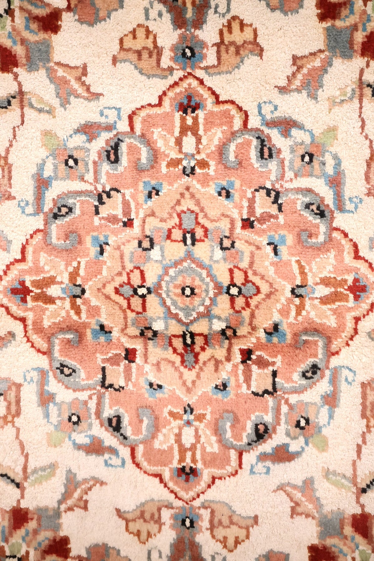 Détail du médaillon en losange rose saumon du tapis PLS, rinceaux bleu-gris et rouge