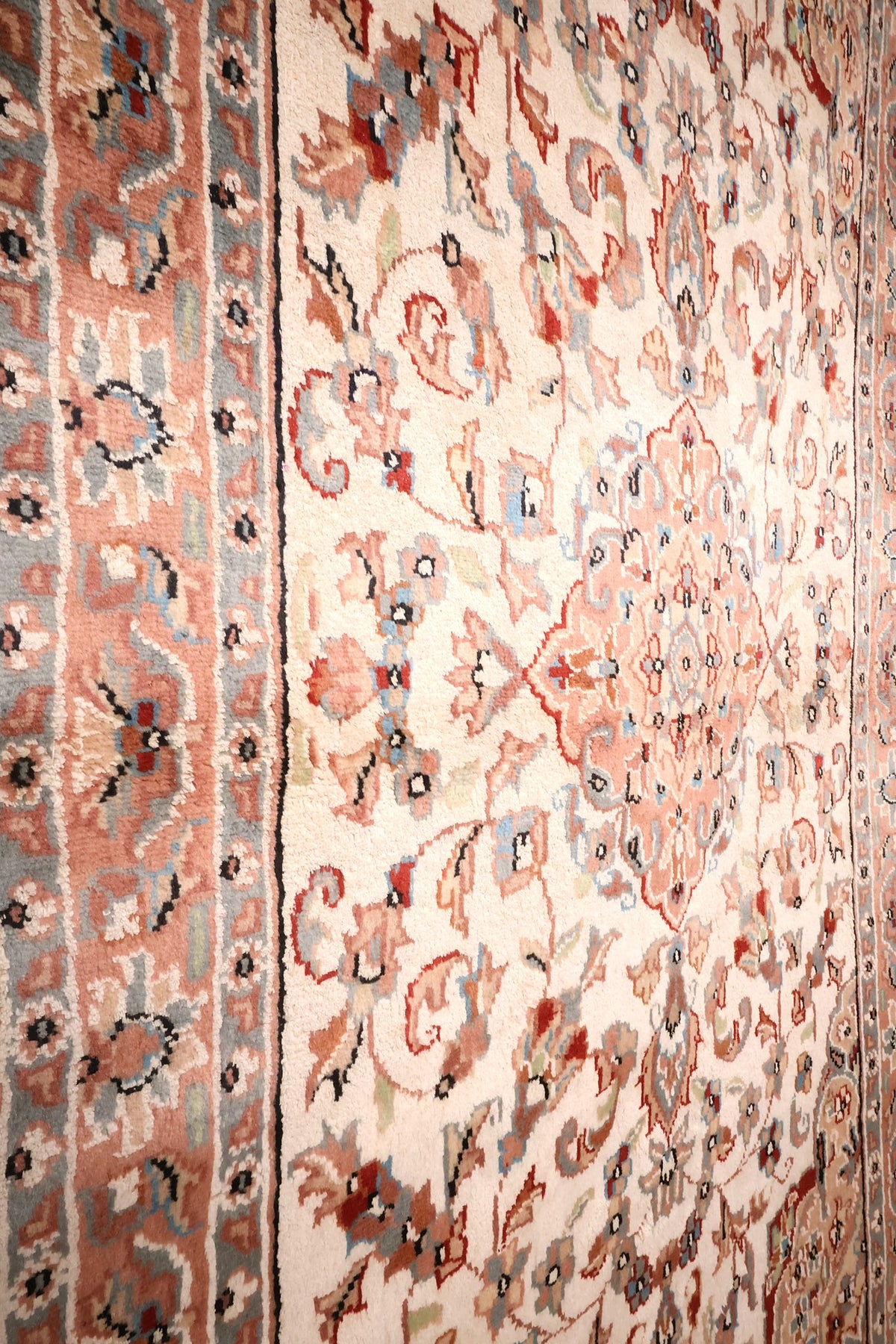 Champ ivoire à palmettes et tiges recourbées du tapis PLS, près de la bordure