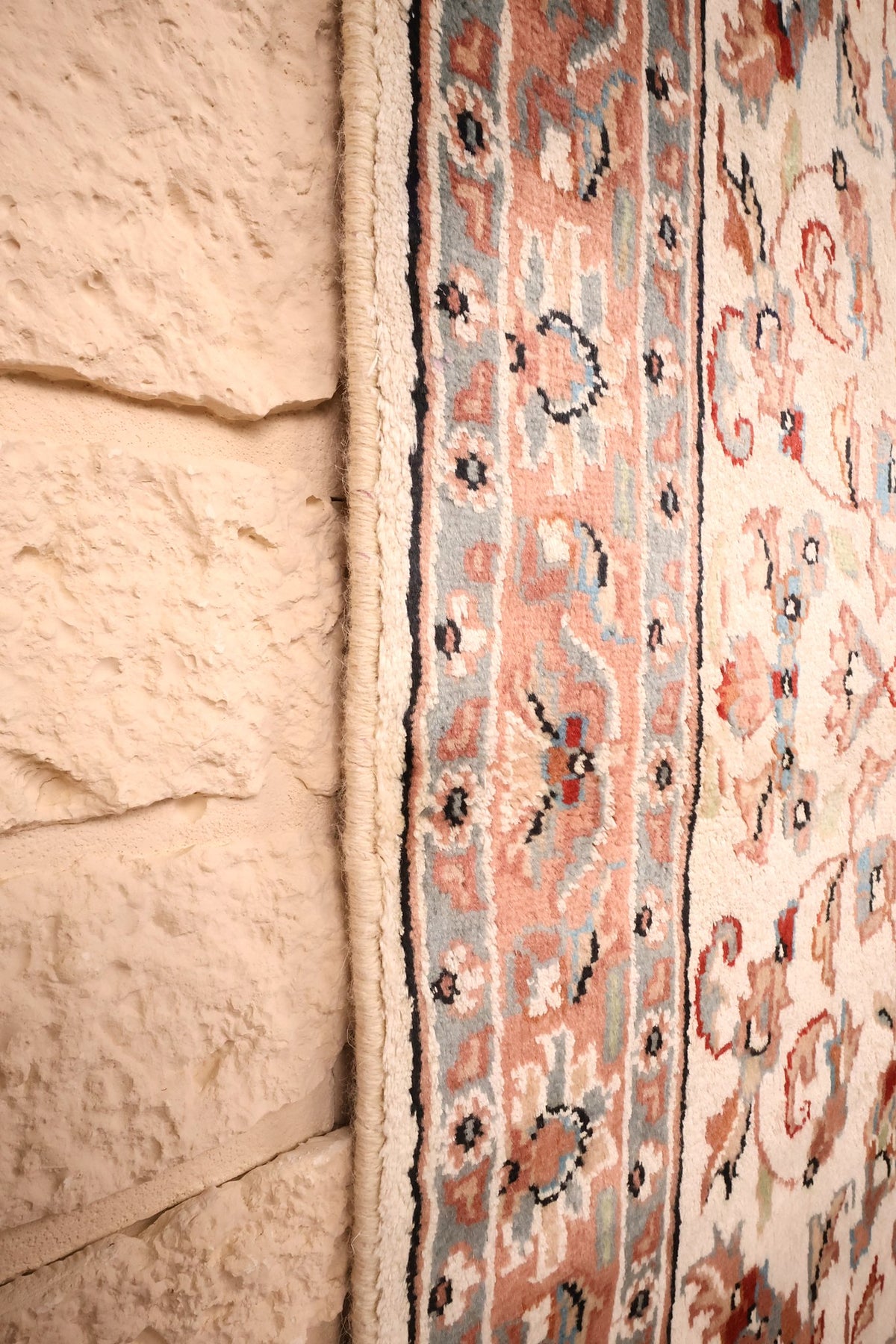 Lisière du tapis PLS beige, filet sombre longeant la bordure florale